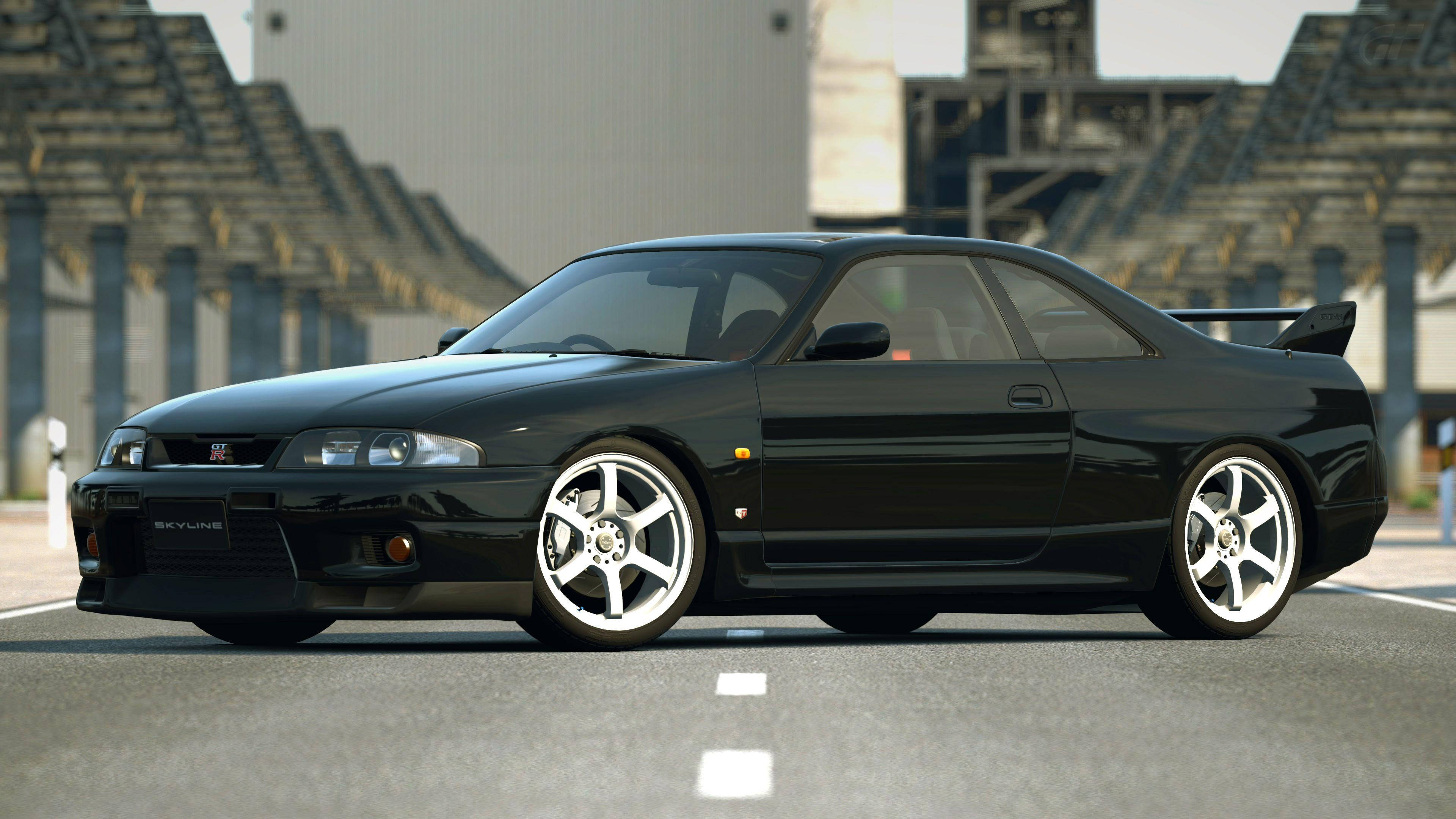 Gtr 桌布 壁紙 — 一輛時尚的黑色日產Skyline GT-R停放在空蕩蕩的賽車場上，背景有看台。