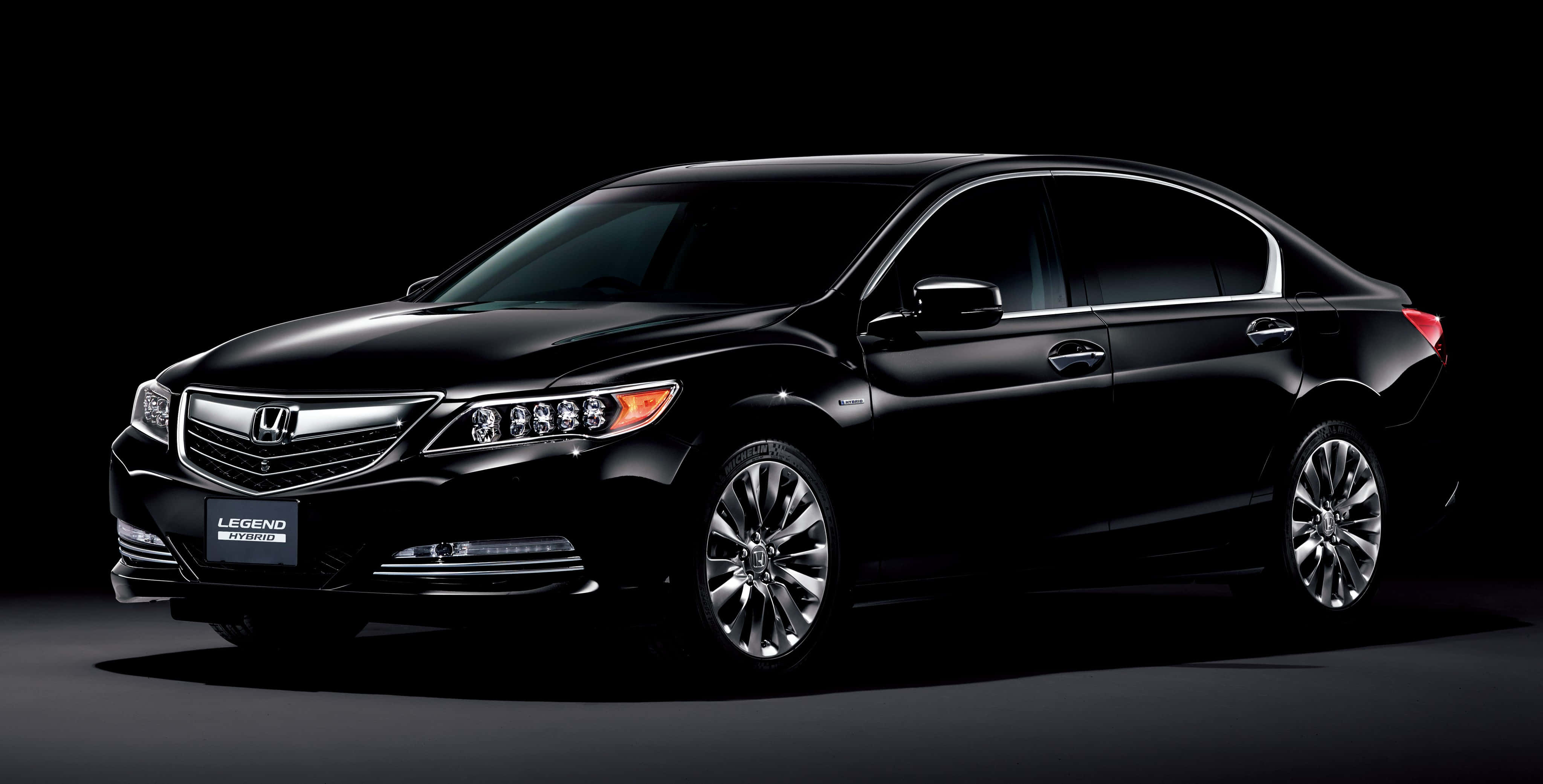 Honda Legend 桌布 壁紙 — 一輛時尚的黑色本田Legend轎車在攝影棚燈光下於深色背景中閃耀，展現其拋光鍍鉻飾件和合金輪圈。