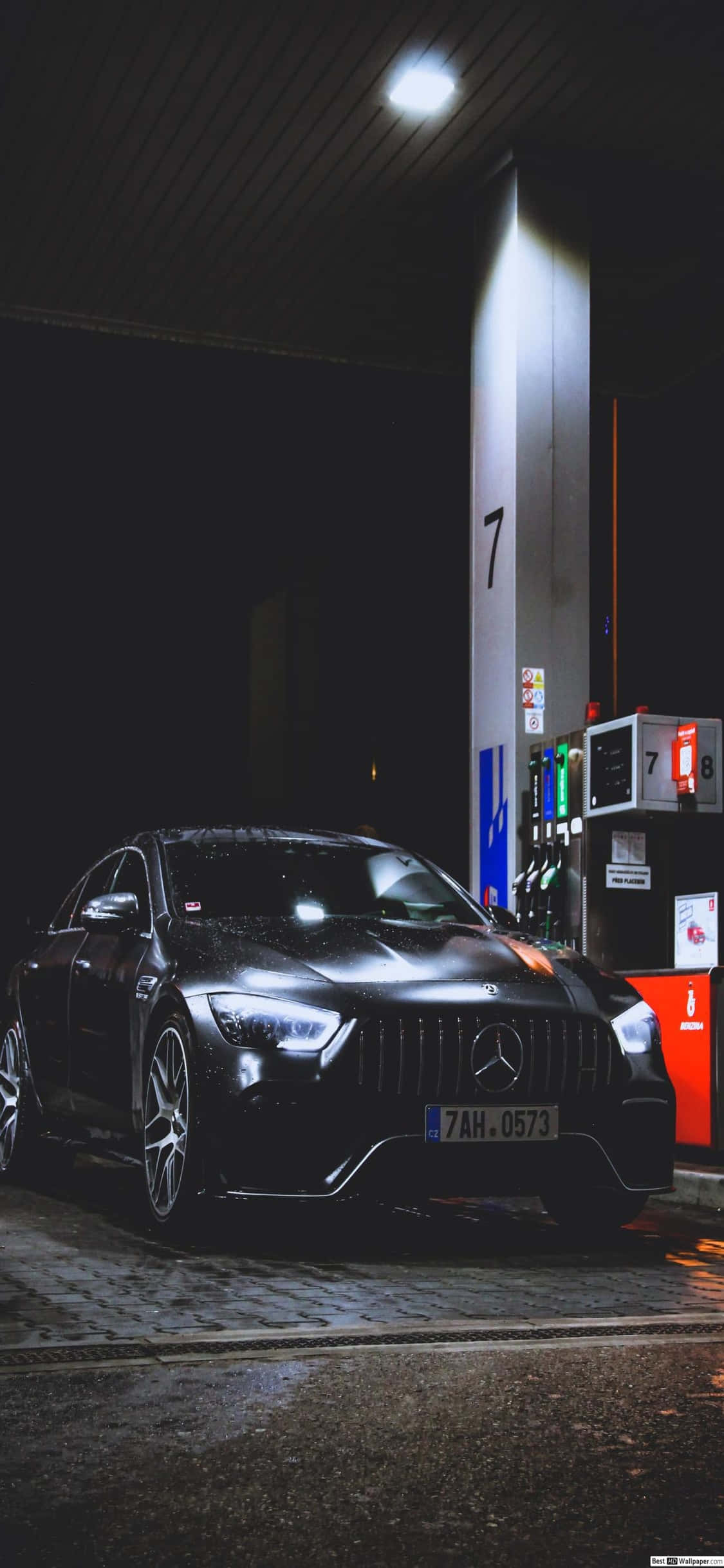 Mercedes 桌布 壁紙 — 一輛時尚的黑色梅賽德斯-AMG在夜間停泊在一個明亮的燈光下的加油站油泵旁。