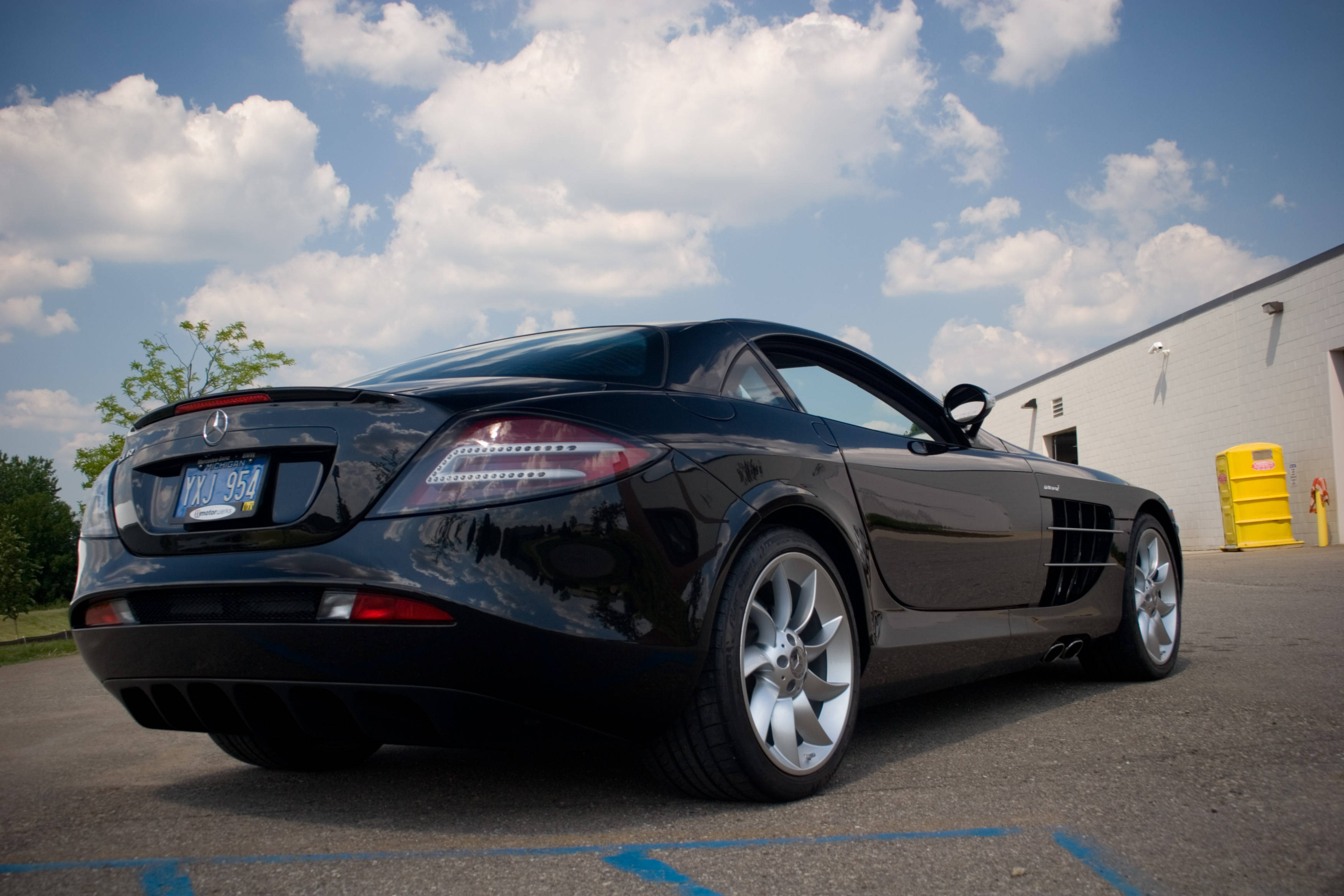 HD mercedes 桌布 壁紙 — 一輛時尚的黑色梅賽德斯SLR麥拿侖跑車停放在戶外，天空湛藍，白雲朵朵。