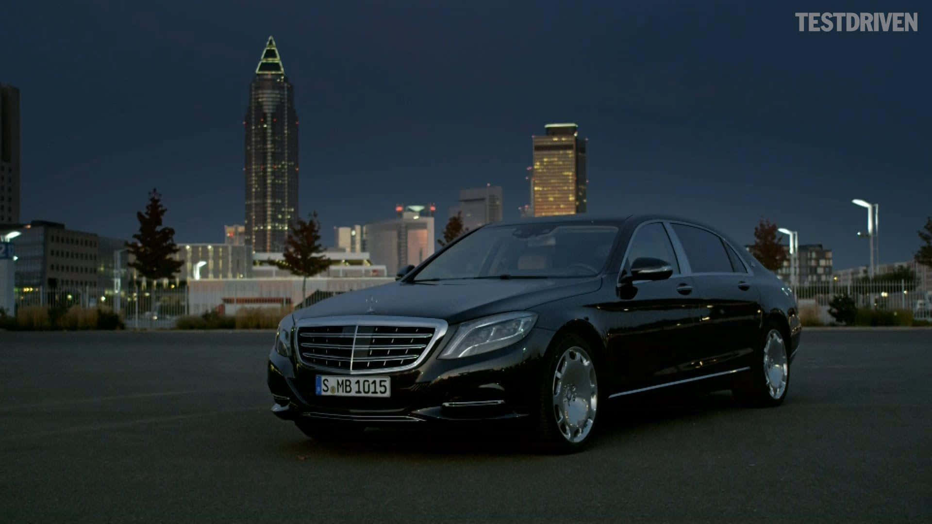 Maybach 桌布 壁紙 — 一輛時尚的黑色梅賽德斯S級轎車在暮色城市燈光下閃耀，背景是燈火通明的摩天大樓。