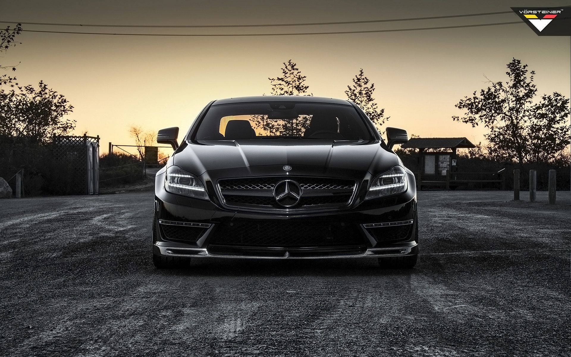 Mercedes Benz Amg 桌布 壁紙 — 一輛時尚的黑色梅賽德斯跑車在寧靜的停車場中，在金色夕陽下閃閃發光。