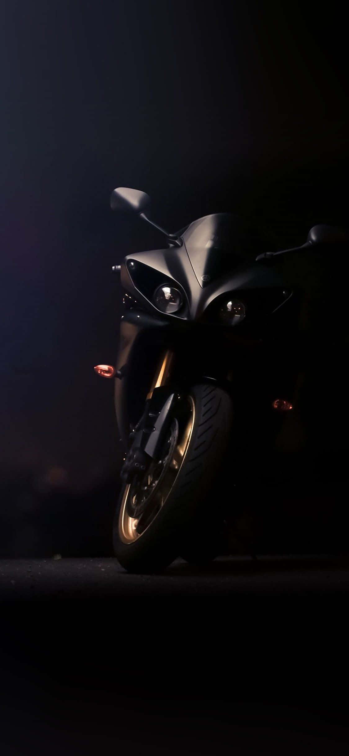 Motorcycle iPhone 桌布 壁紙 — 一輛時尚的黑色機車，在黑暗煙霧背景中被戲劇性的聚光燈照亮。