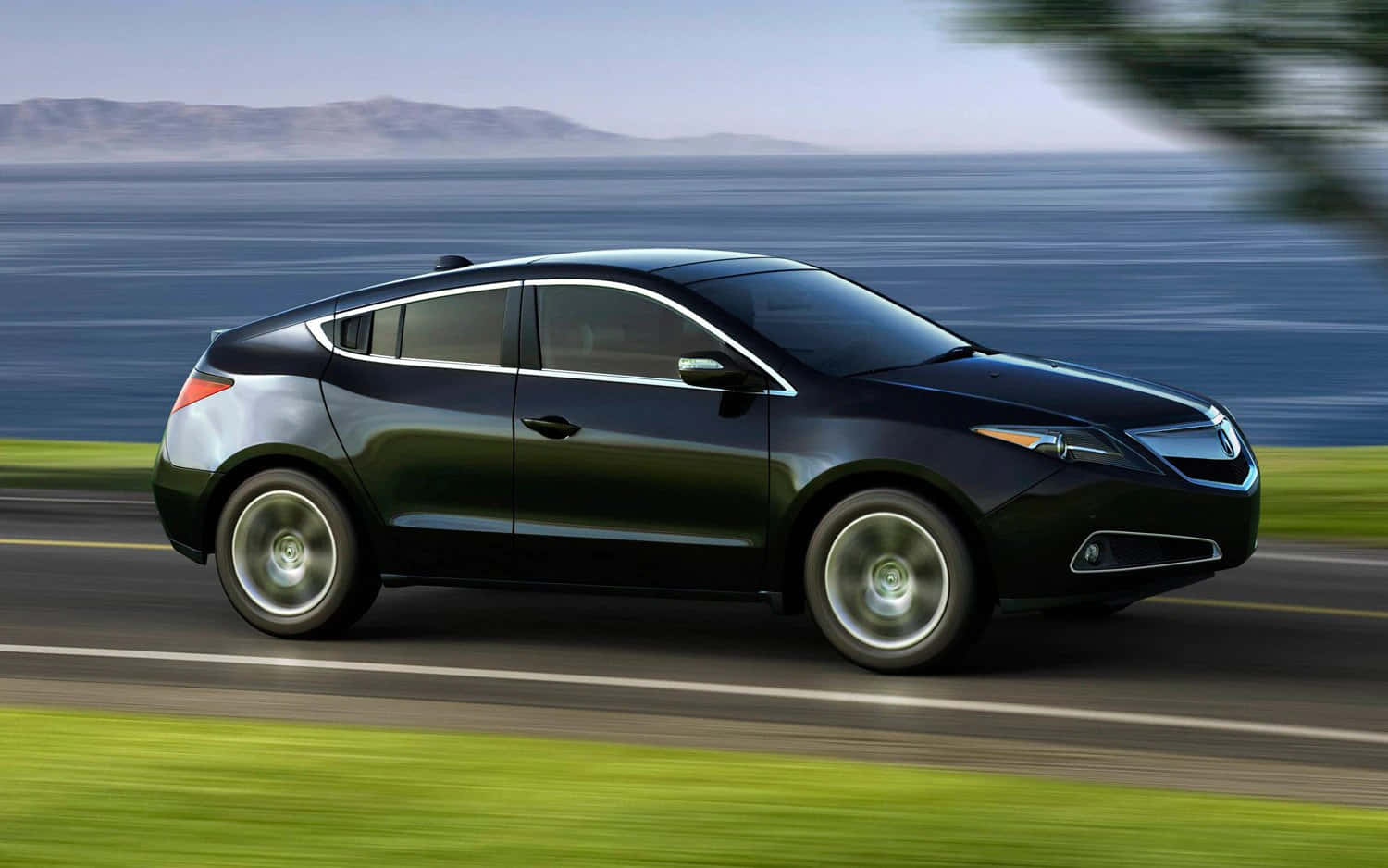 Acura 桌布 壁紙 — 一輛時尚的黑色汽車沿著海岸公路飛馳，背景是模糊的綠色草地和藍色海洋。