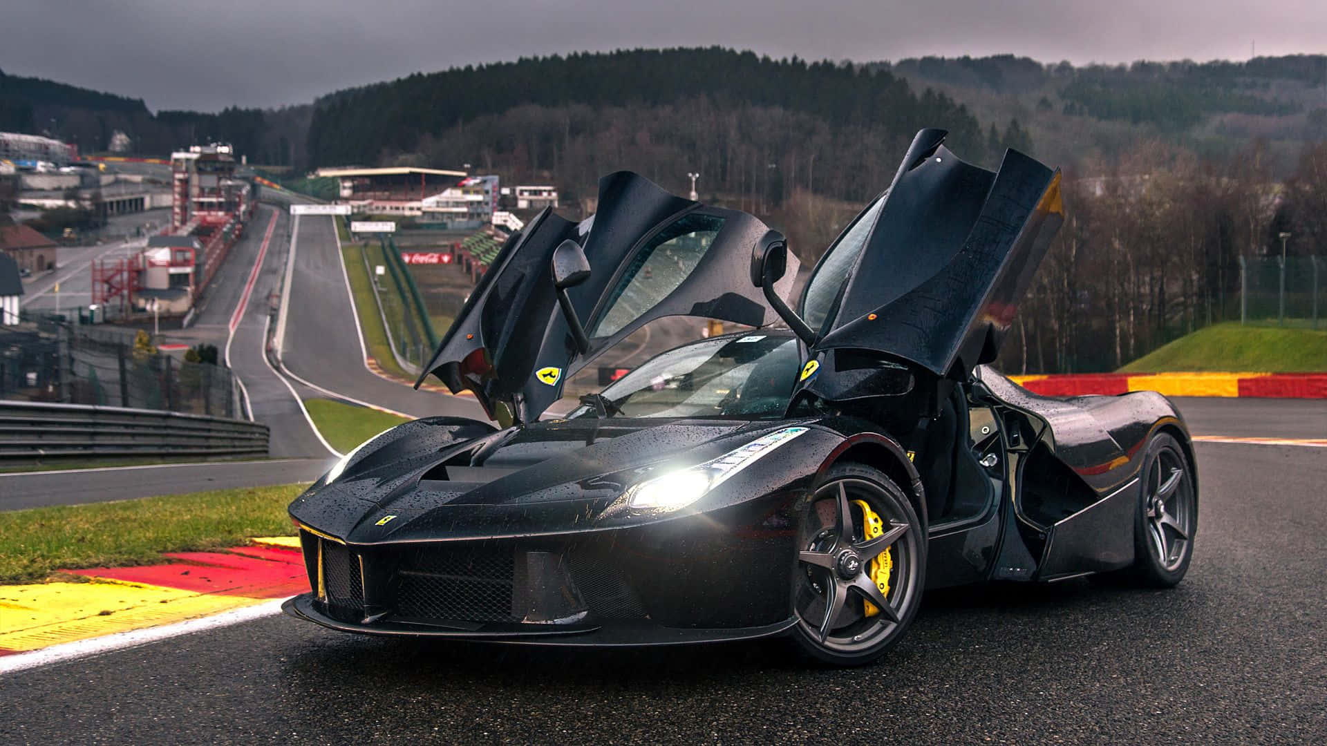 Ferrari Laferrari 桌布 壁紙 — 一輛時尚的黑色法拉利 LaFerrari 打開鷗翼車門，停在潮濕的賽車場上，天空多雲。