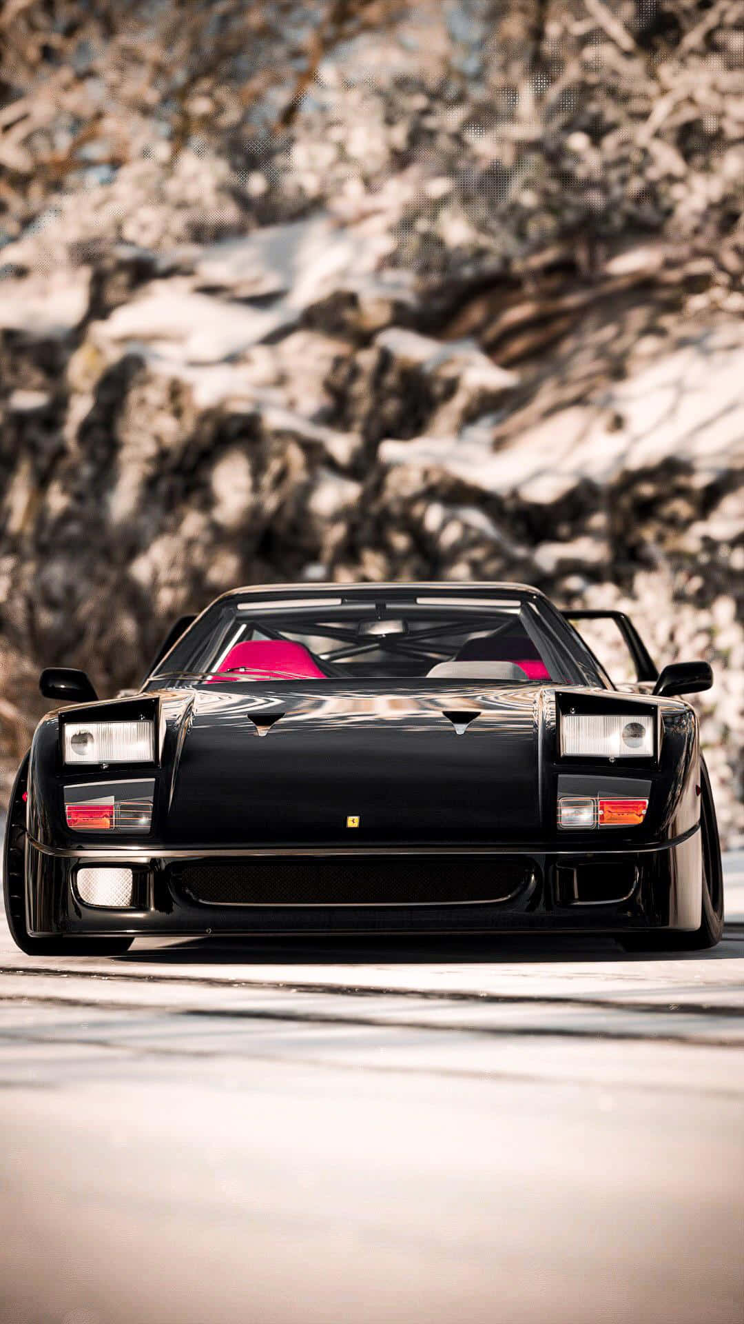 Vintage Ferrari 桌布 壁紙 — 一輛時尚的黑色法拉利 Testarossa 配備粉紅色內裝，停放在白雪覆蓋的山路上，背景是崎嶇的冬季懸崖。