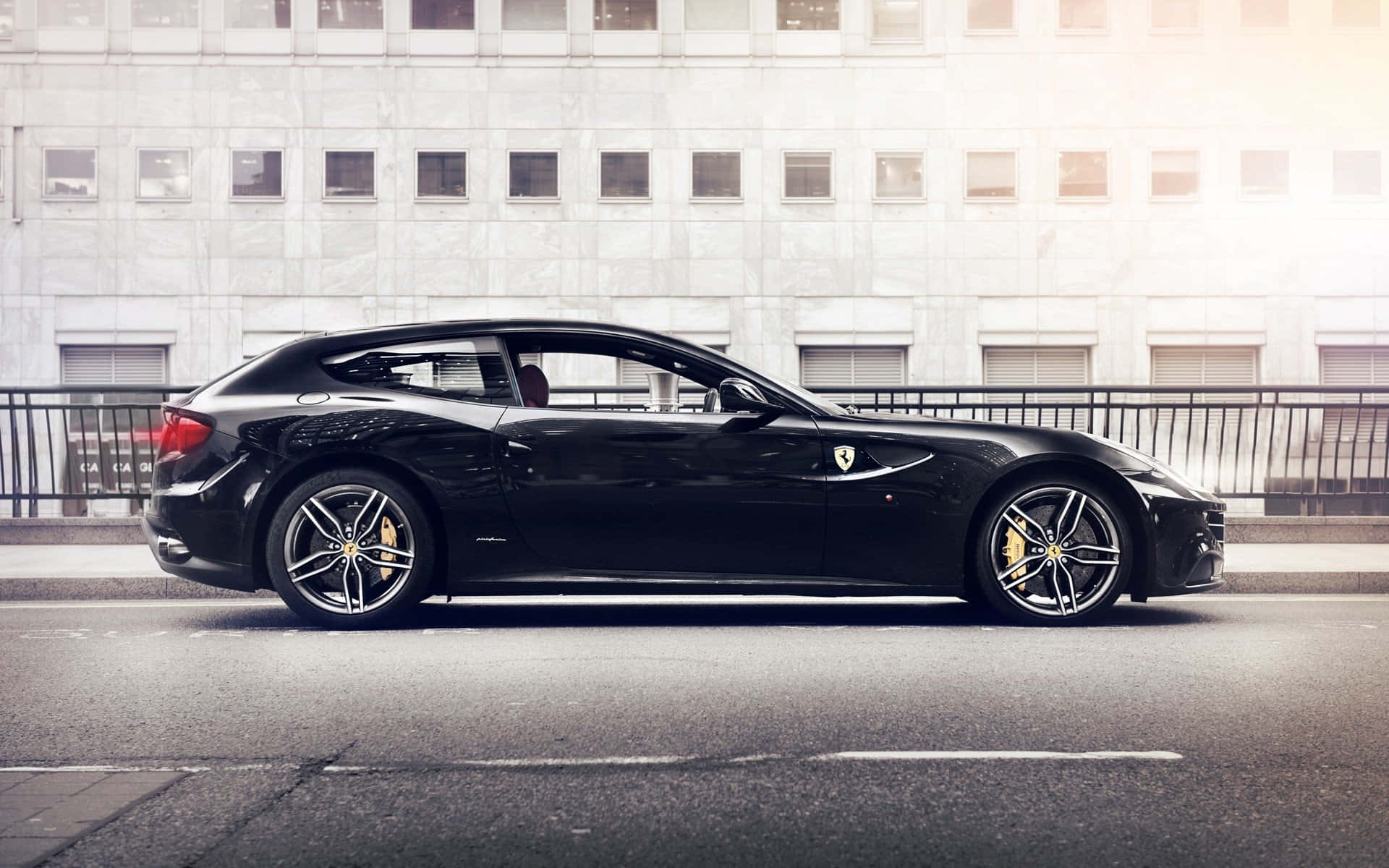 Ferrari Ff 桌布 壁紙 — 一輛時尚的黑色法拉利FF運動旅行車停在城市街道上，背景是現代建築。