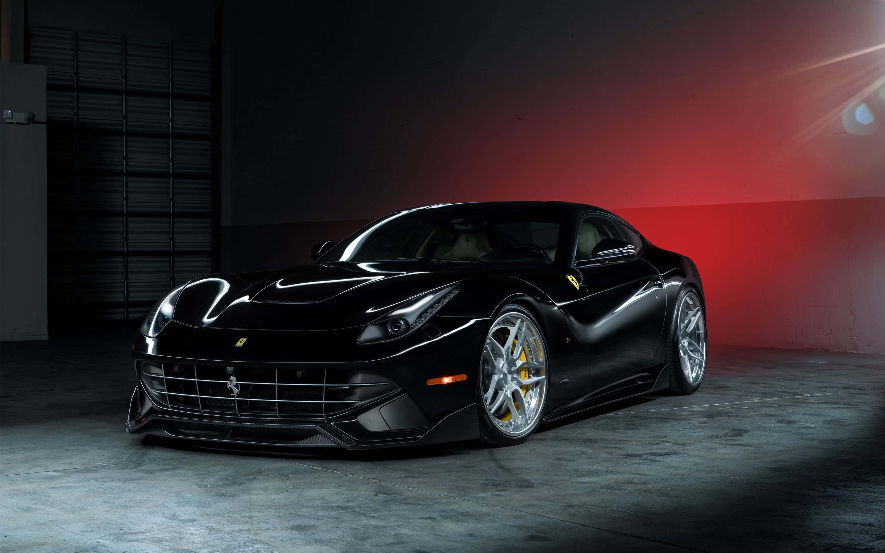 Ferrari F12 Berlinetta 桌布 壁紙 — 一輛時尚的黑色法拉利跑車在黑暗的工業車庫中，在戲劇性的紅色和白色燈光下閃閃發光。