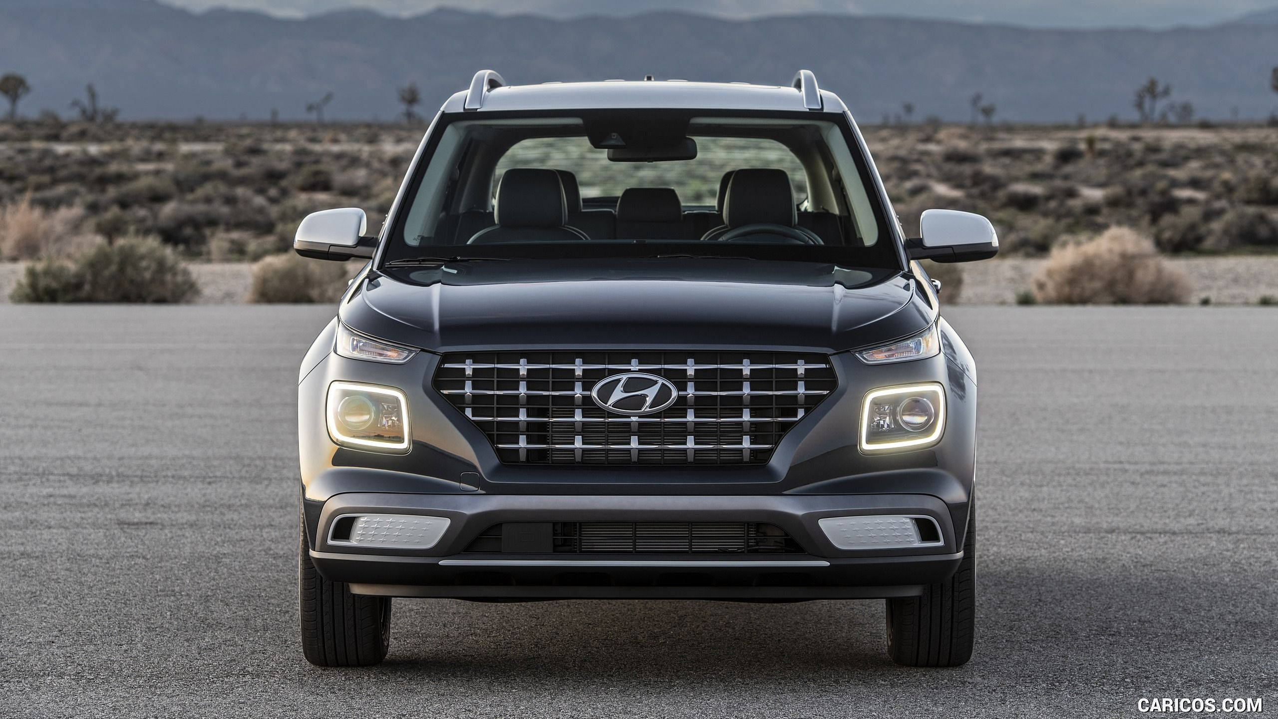 Hyundai 桌布 壁紙 — 一輛時尚的黑色現代SUV在沙漠公路上向前行駛，背景是山脈，光線柔和。