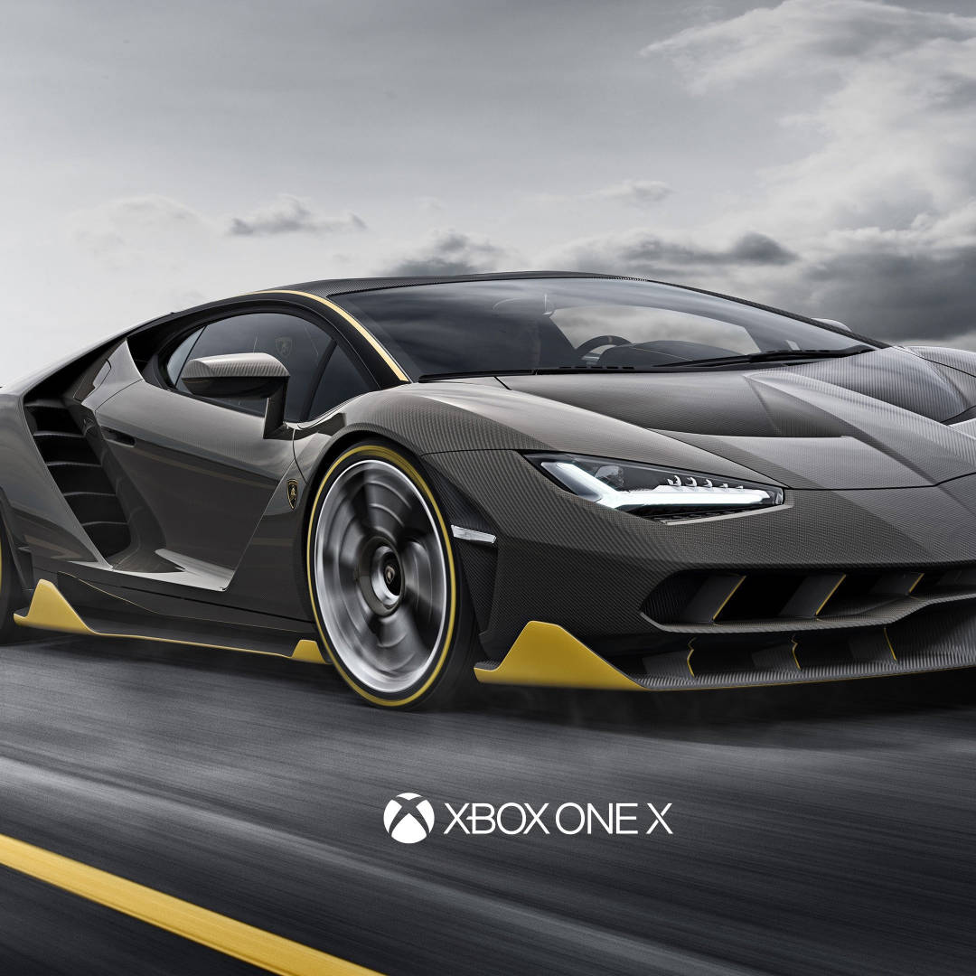 Xbox 桌布 壁紙 — 一輛時尚的黑色碳纖維跑車帶有黃色點綴，在多雲的天空下沿著道路疾馳。