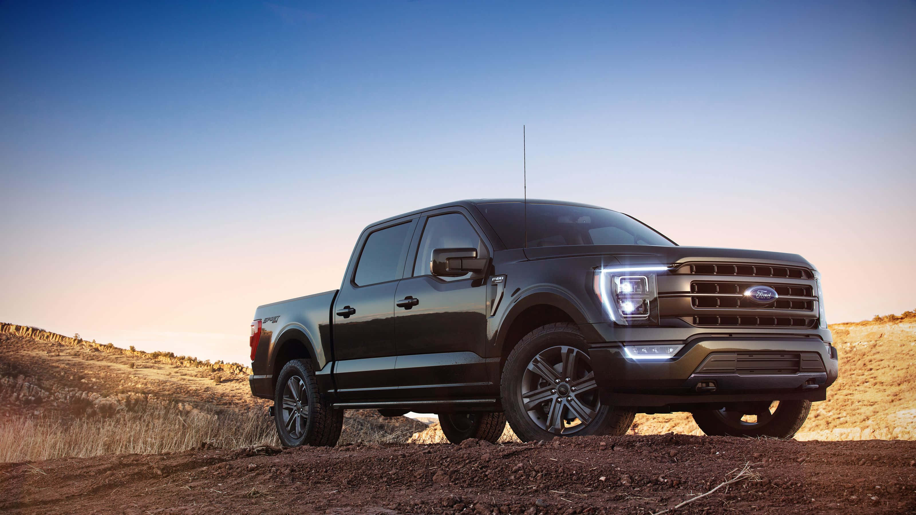 Ford F 150 桌布 壁紙 — 一輛時尚的黑色福特F-150 pickup卡車在日落時分，停放在崎嶇的泥土小徑上，背景是漸層的天空。