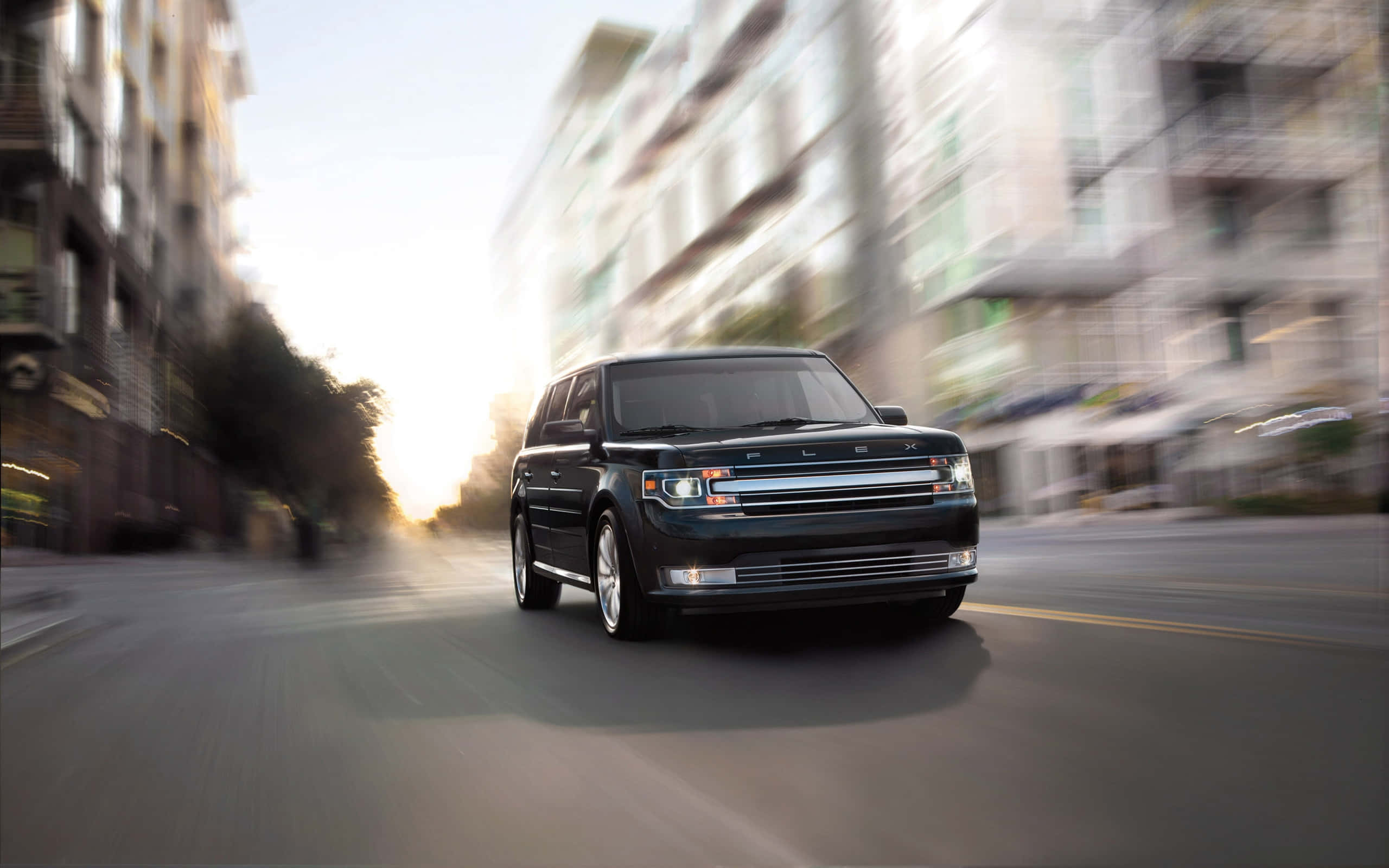 Ford Flex 桌布 壁紙 — 一輛時尚的黑色福特Flex SUV在城市的街道上飛馳，建築物呈現動態模糊，伴隨著溫暖的日落餘暉。
