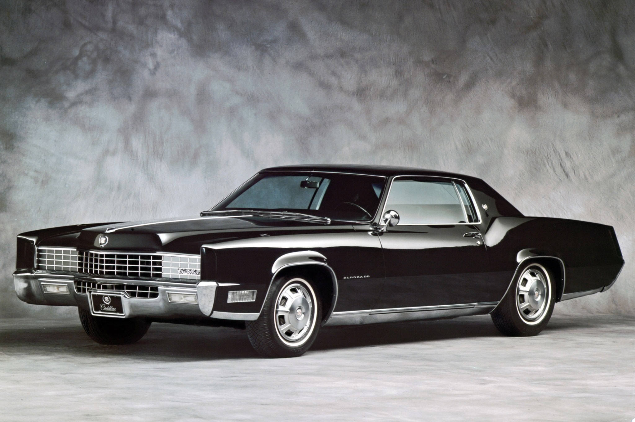 Cadillac 桌布 壁紙 — 一輛時尚的黑色經典凱迪拉克Coupe de Ville在攝影棚燈光下閃耀，背景為紋理灰色。