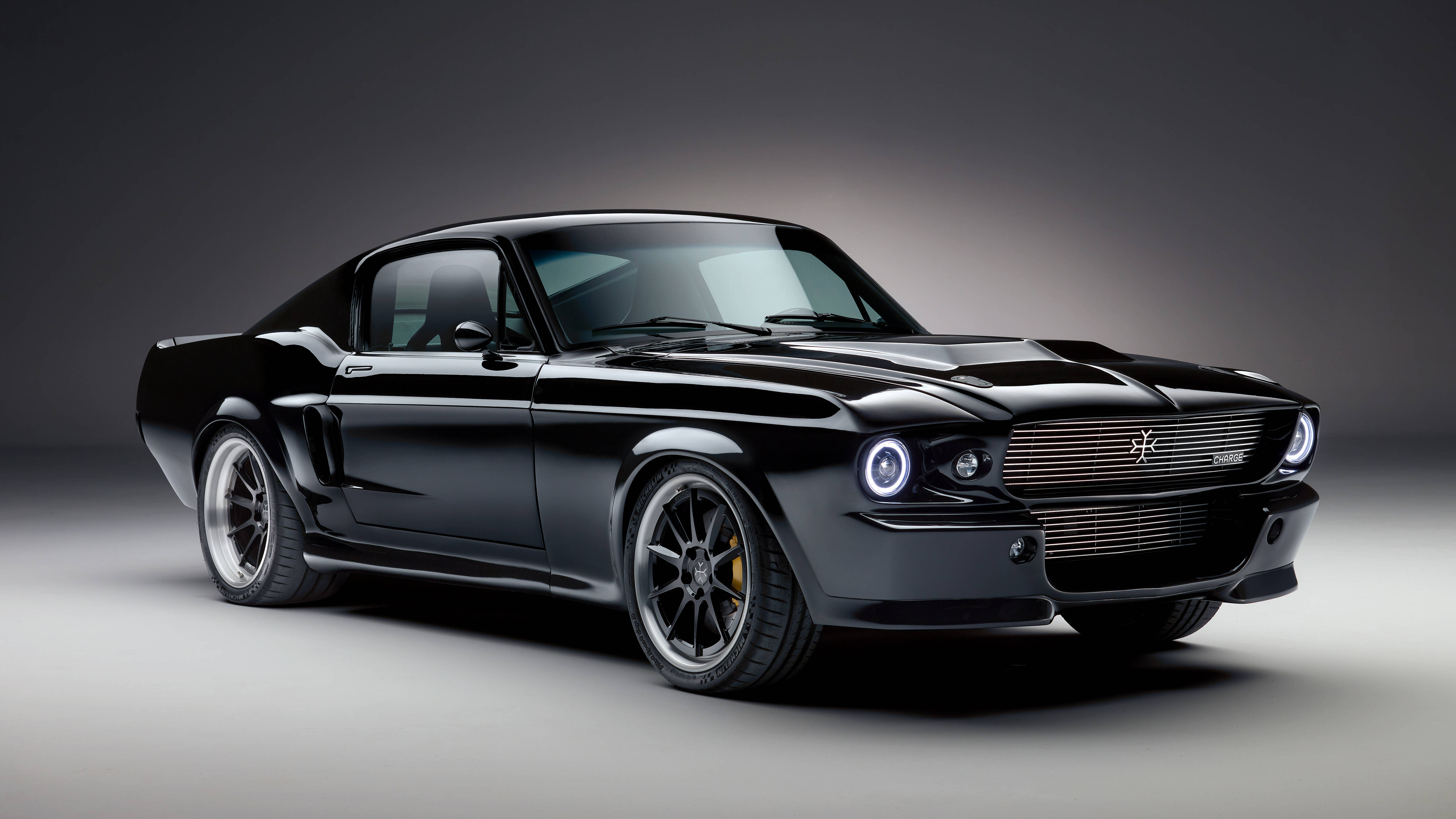 Cool Mustang 桌布 壁紙 — 一輛時尚的黑色經典肌肉車，帶有發光的頭燈和定制輪圈，在極簡灰色工作室背景前擺拍。