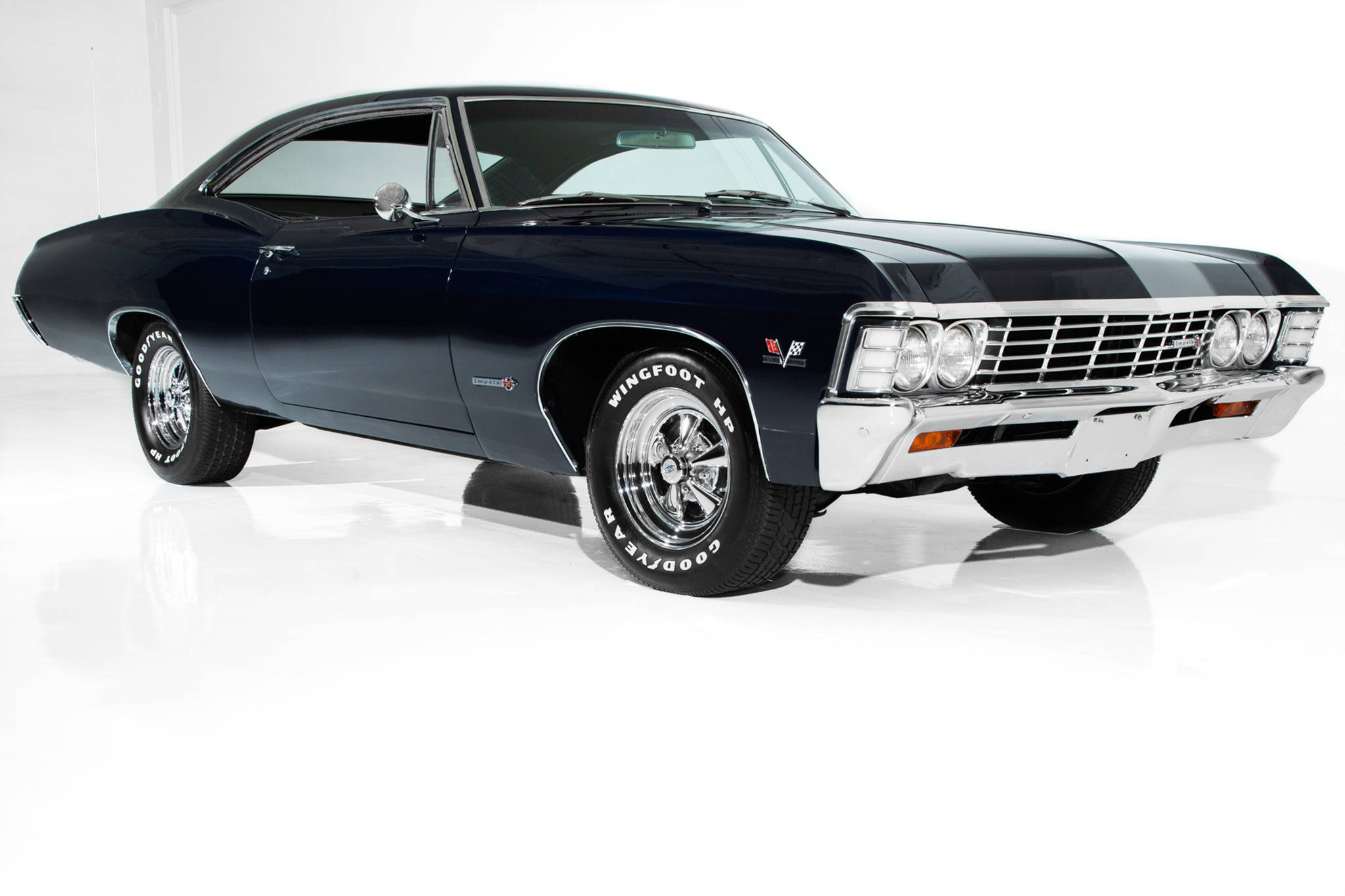 chevrolet impala 1967 桌布 壁紙 — 一輛時尚的黑色經典肌肉車，帶有鍍鉻裝飾和白色牆壁輪胎，停在反射性白色工作室地板上。