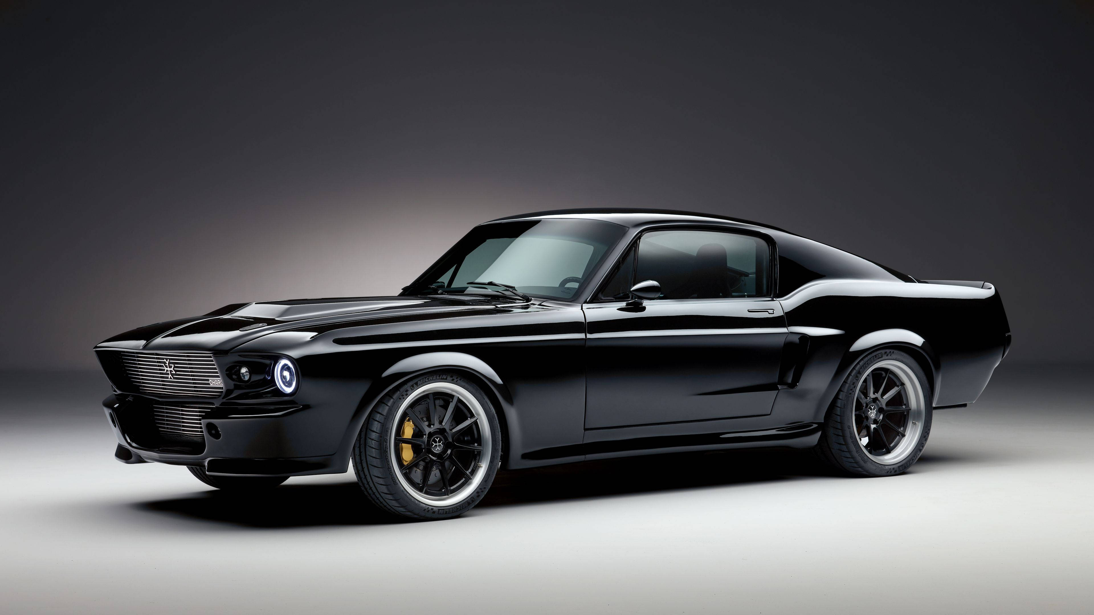 Cool Mustang 桌布 壁紙 — 一輛時尚的黑色經典肌肉車，配備黃色制動卡鉗，在戲劇性燈光的攝影棚中展示。