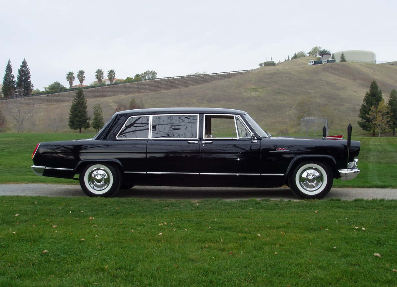 Hongqi 桌布 壁紙 — 一輛時尚的黑色經典轎車，帶有鍍鉻飾條和白牆輪胎，停放在陰天下的草地上。
