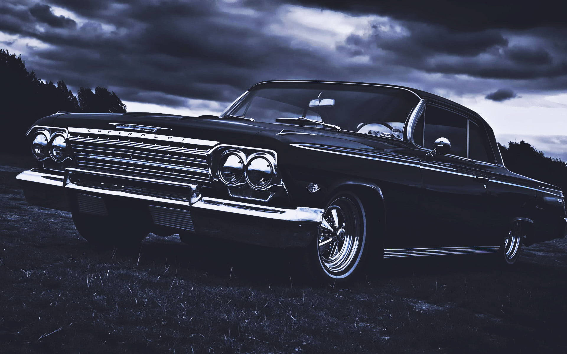 chevrolet impala 1967 桌布 壁紙 — 一輛時尚的黑色經典雪佛蘭轎車在充滿戲劇性雲彩的暮色天空下閃閃發光。