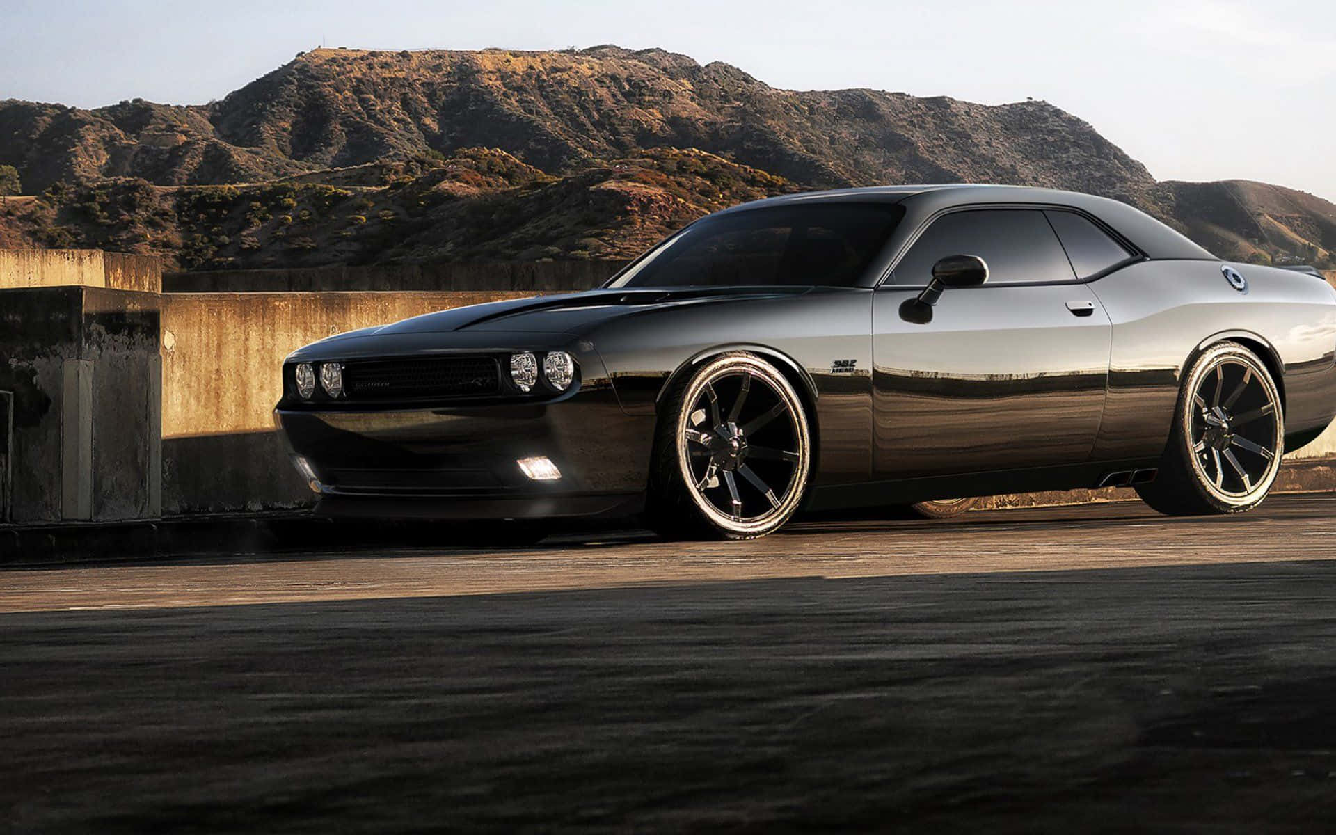 Dodge Charger 桌布 壁紙 — 一輛時尚的黑色肌肉車配備定制輪圈，停放在混凝土觀景台上，背景是陽光照耀的乾燥山丘。