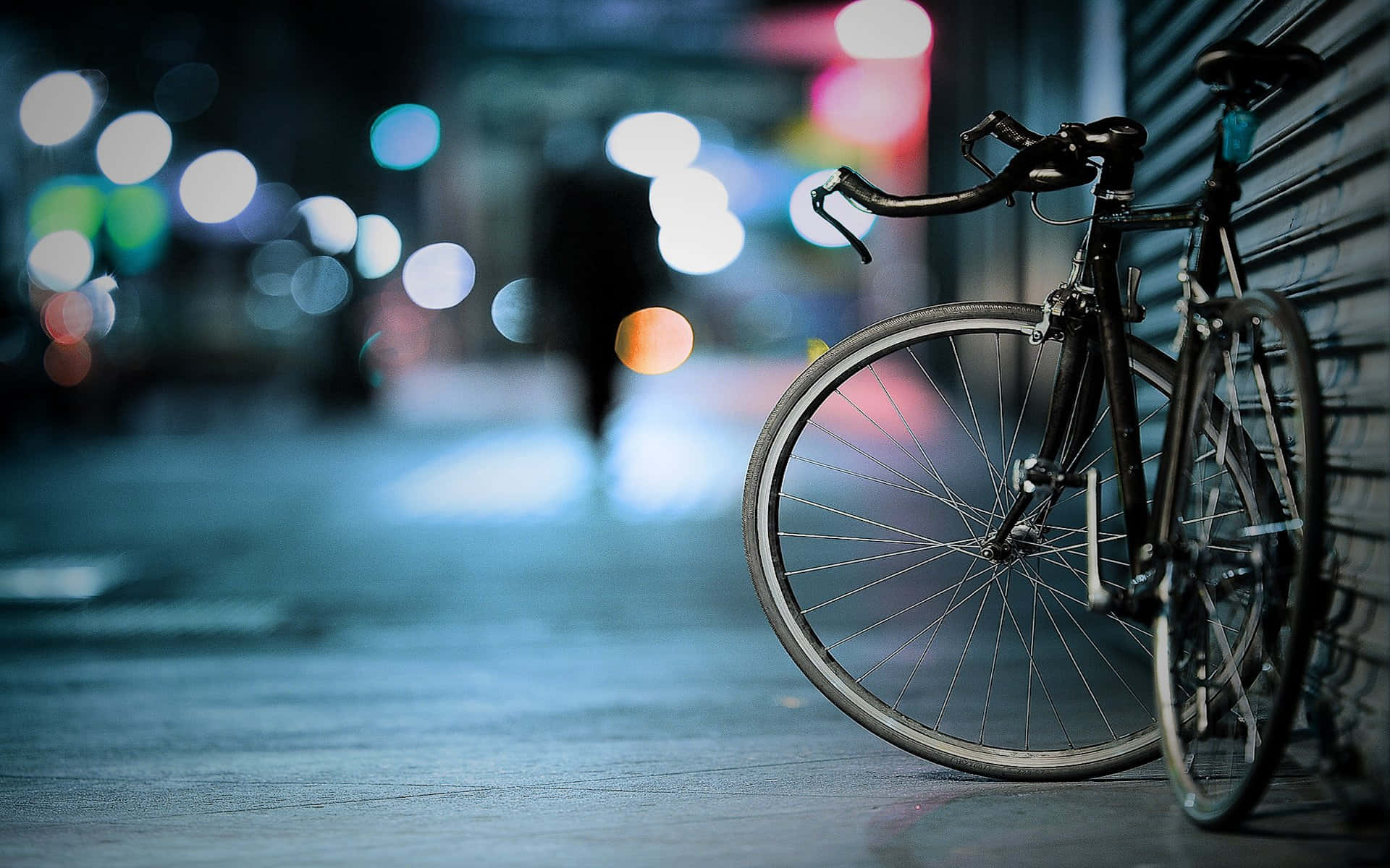 Bicycle 桌布 壁紙 — 一輛時尚的黑色腳踏車靠在濕漉漉的城市街道上的金屬百葉窗上，背景是閃爍的散景燈光。