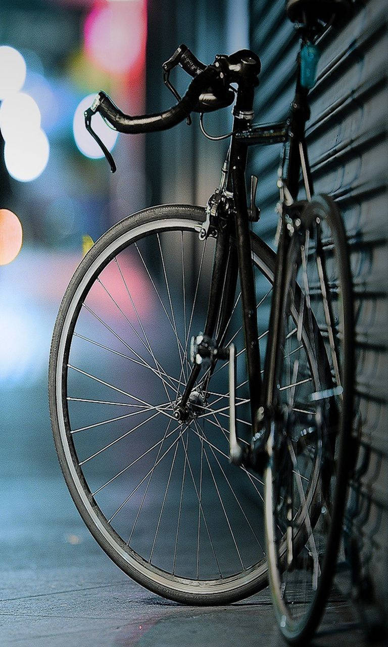 最佳高畫質 桌布 壁紙 — 一輛時尚的黑色自行車在夜晚的街燈下靠著磚牆。