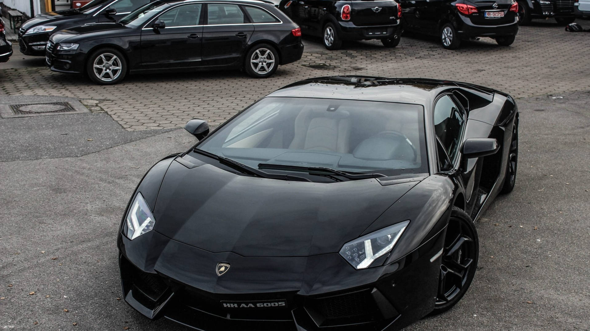 Lamborghini 4K 桌布 壁紙 — 一輛時尚的黑色藍寶堅尼Aventador跑車停放在停車場，與其他豪華車輛一起，天空多雲。