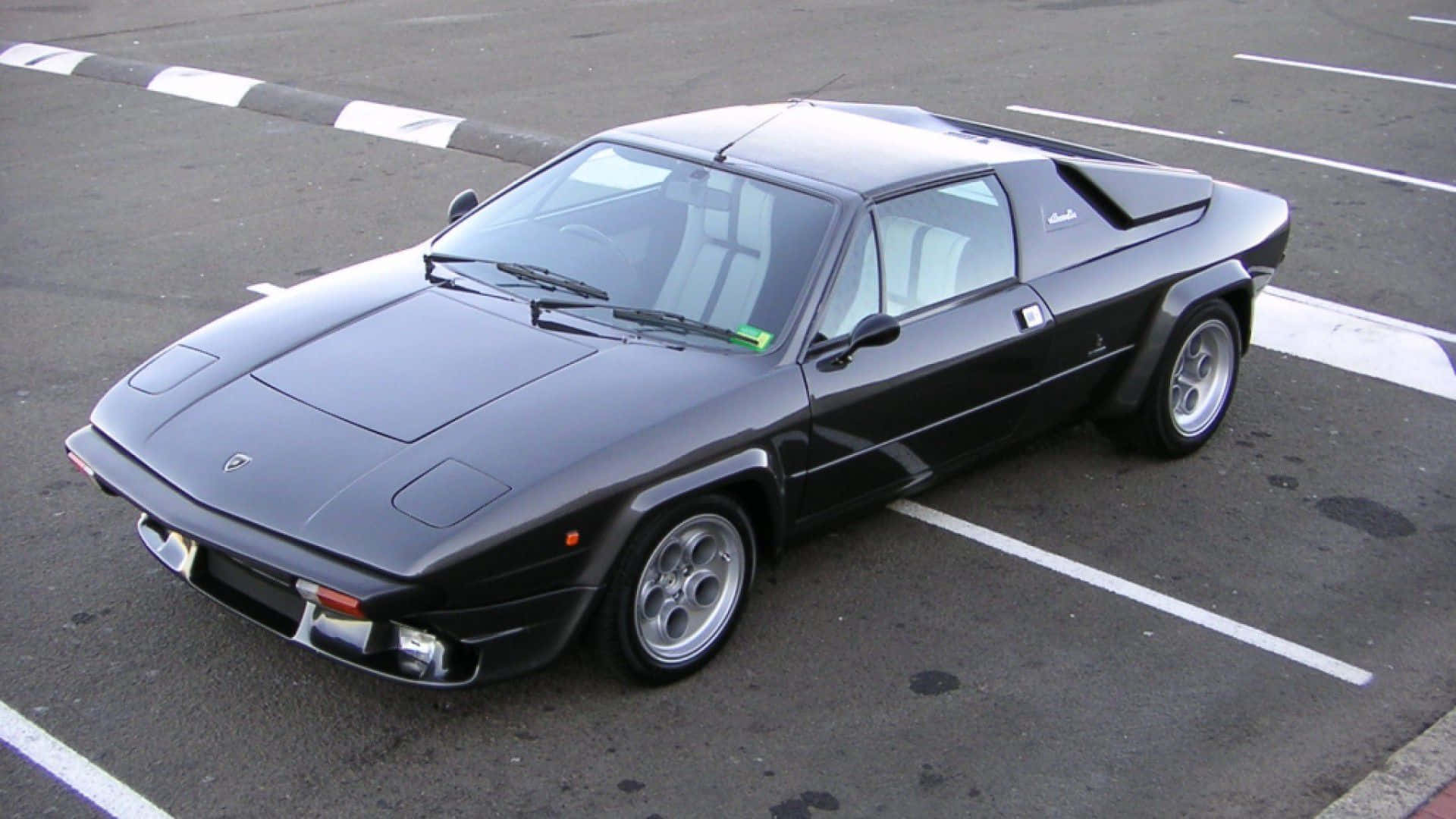 Lamborghini Silhouette 桌布 壁紙 — 一輛時尚的黑色藍寶堅尼Countach斜停在鋪有白線的柏油停車場上。