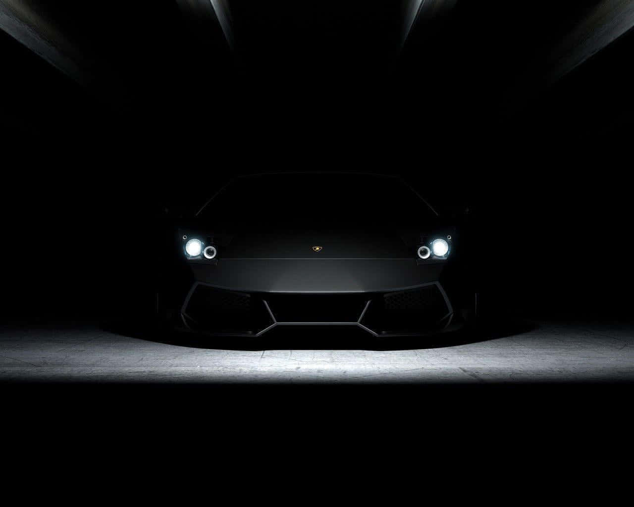 Black And White Car 桌布 壁紙 — 一輛時尚的黑色藍寶堅尼在黑暗而戲劇性的隧道環境中，以發光的車頭燈向前凝視。