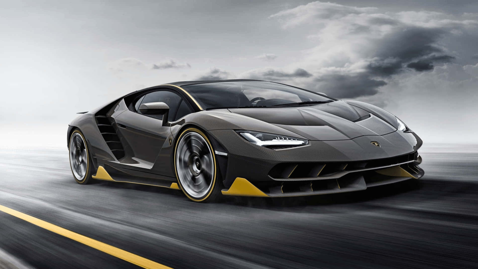 1080p Forza Motorsport 7 桌布 壁紙 — 一輛時尚的黑色藍寶堅尼跑車帶有黃色點綴，在暴風雨灰濛的天空下在濕滑的道路上疾馳。