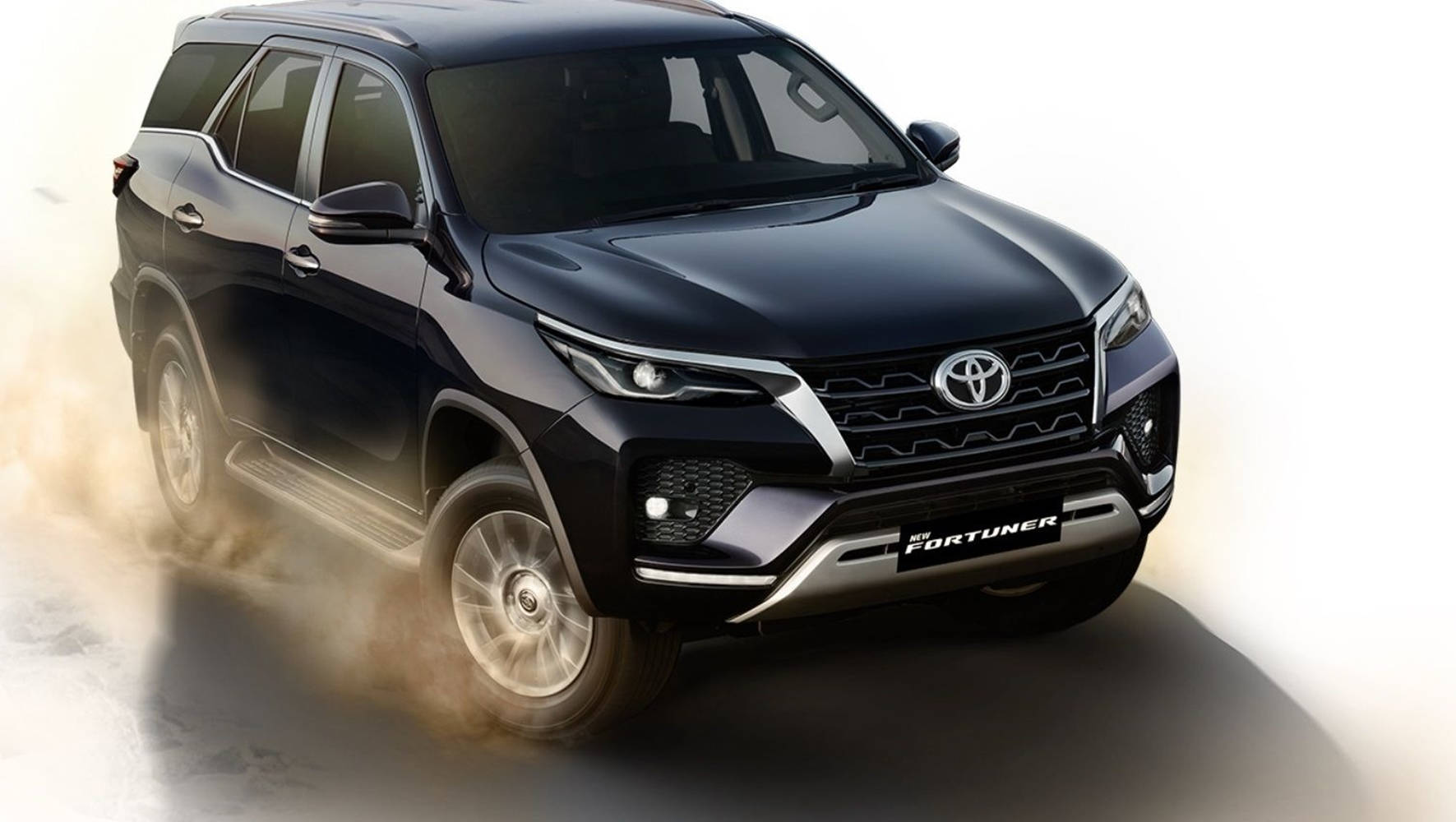 Toyota 桌布 壁紙 — 一輛時尚的黑色豐田 Fortuner SUV 在淺灰色表面上向前行駛，揚起灰塵，背景為亮白色。