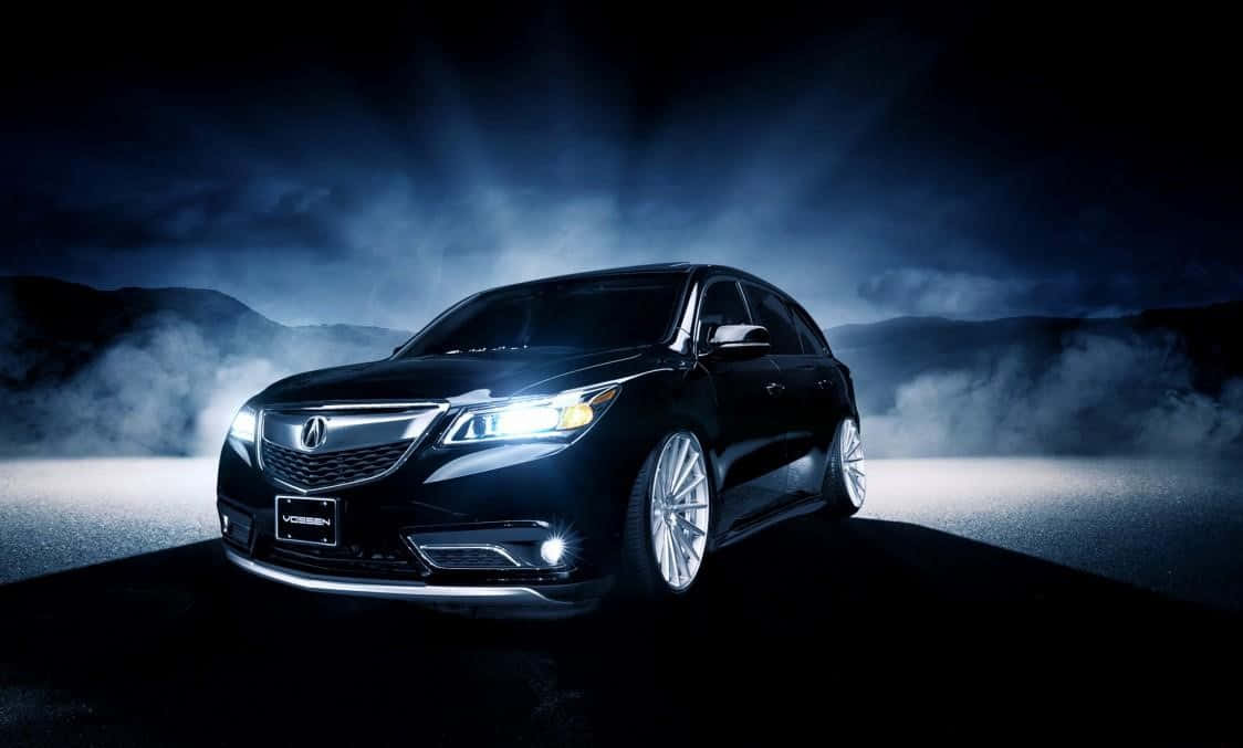 Acura Mdx 桌布 壁紙 — 一輛時尚的黑色豪華轎車在夜間戲劇性的車頭燈下，以霧氣繚繞的山巒為背景閃耀著光芒。