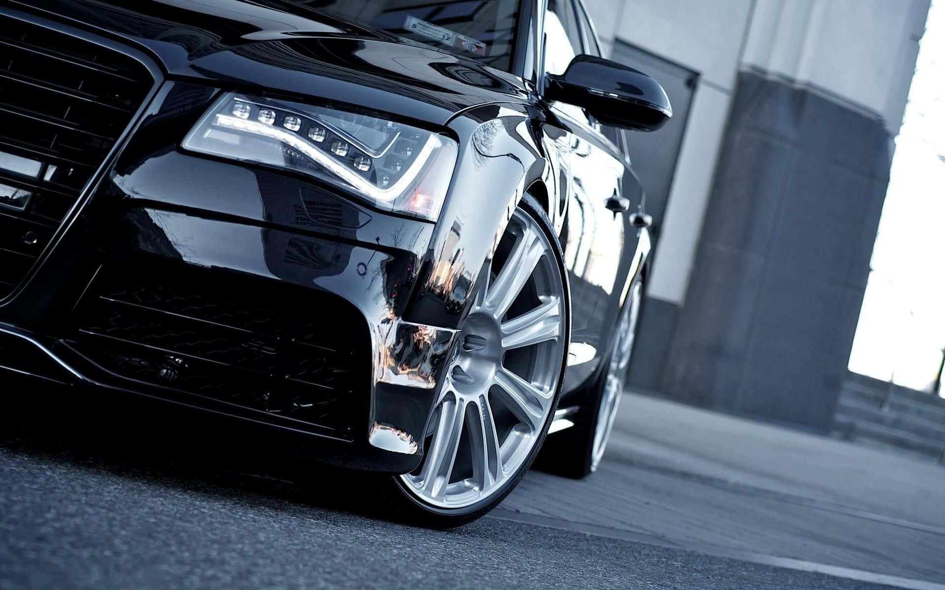 Audi S8 桌布 壁紙 — 一輛時尚的黑色豪華轎車配備定制銀色輪圈，在城市日光下閃閃發光，其銳利的線條和拋光表面反射出粗糙的城市景觀。