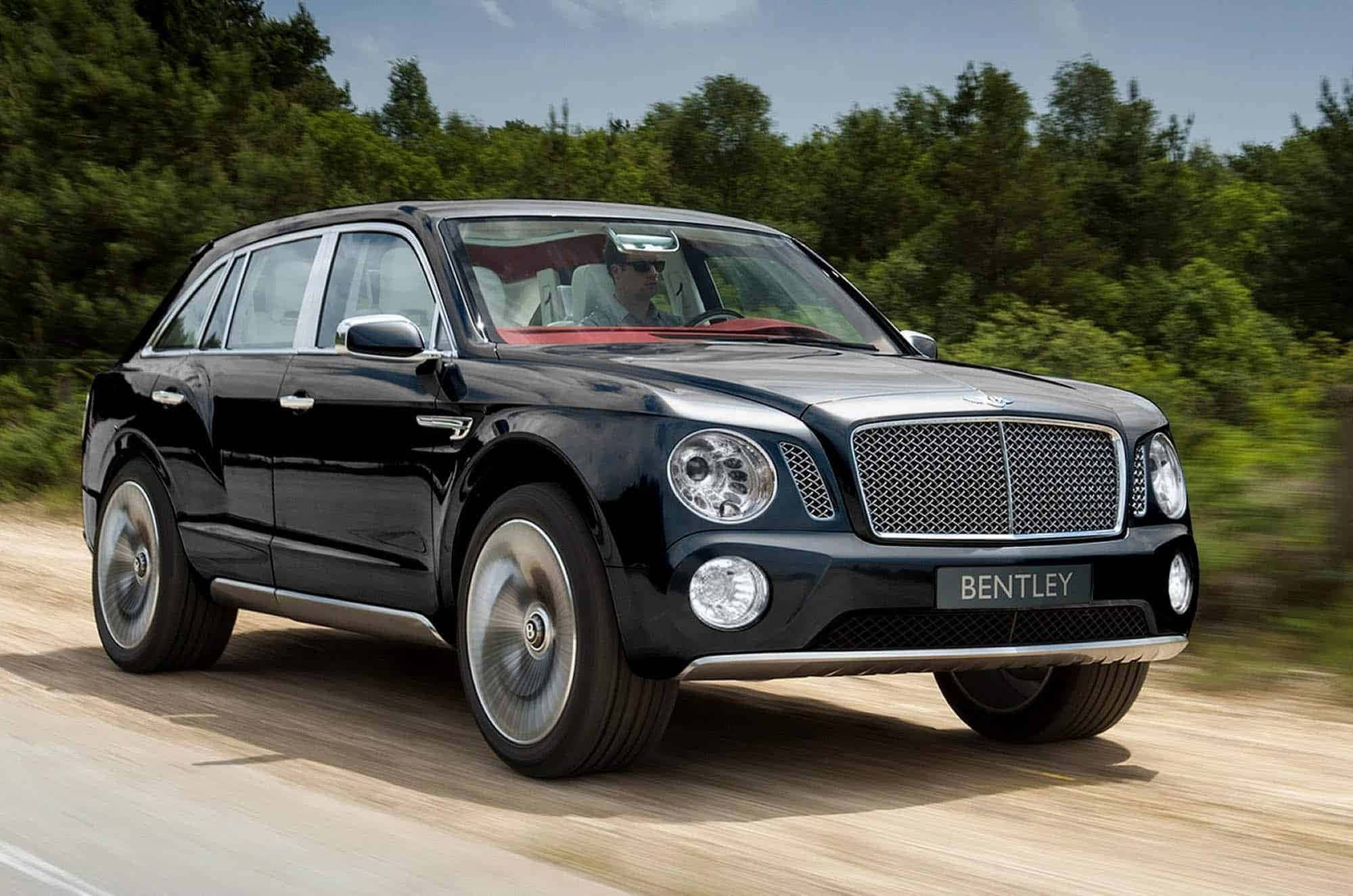 賓利 桌布 壁紙 — 一輛時尚的黑色賓利 Bentayga SUV 在陽光明媚的森林道路上飛馳，車輪帶有動態模糊效果，背景是綠樹。