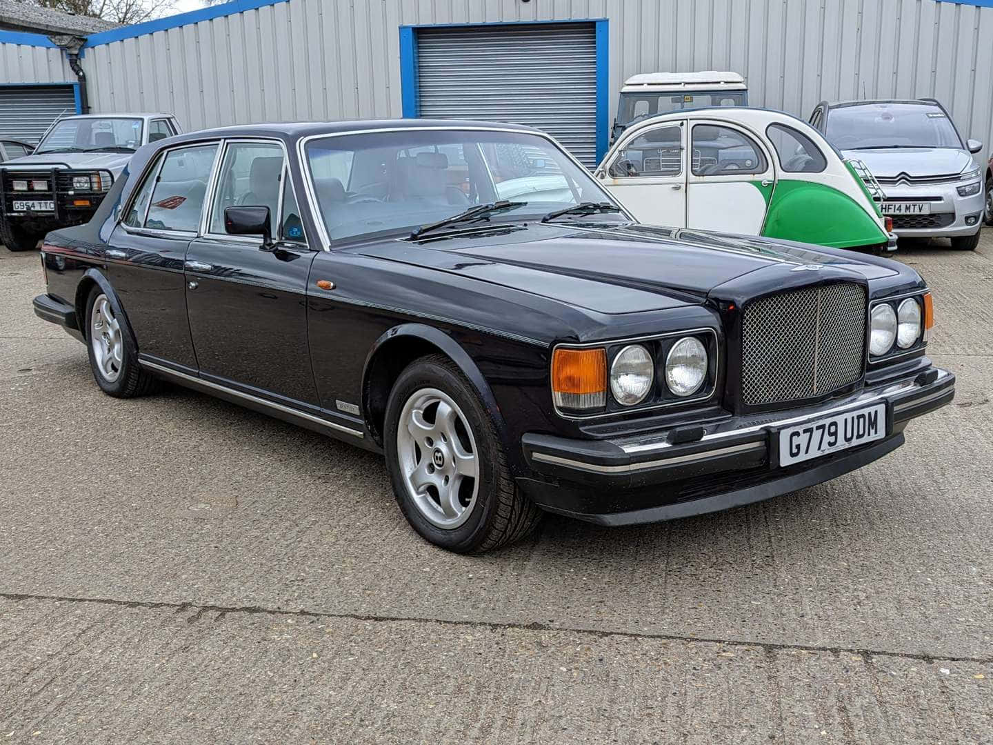 Bentley Eight 桌布 壁紙 — 一輛時尚的黑色賓利 Turbo R 轎車停在混凝土上，背景有其他經典汽車。