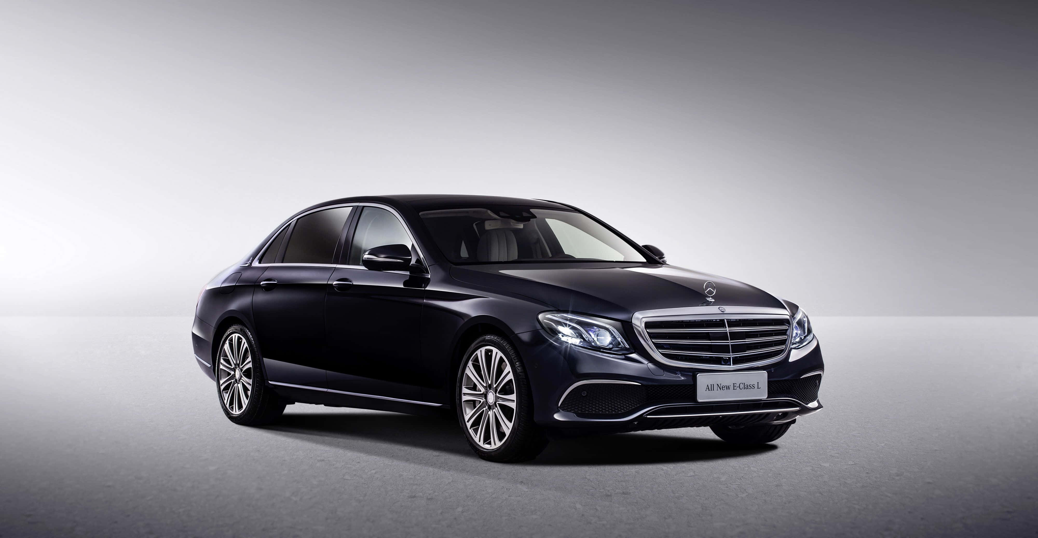 Mercedes Benz Clase E 桌布 壁紙 — 一輛時尚的黑色賓士E-Class轎車在攝影棚燈光下，在極簡灰色背景前閃閃發光。