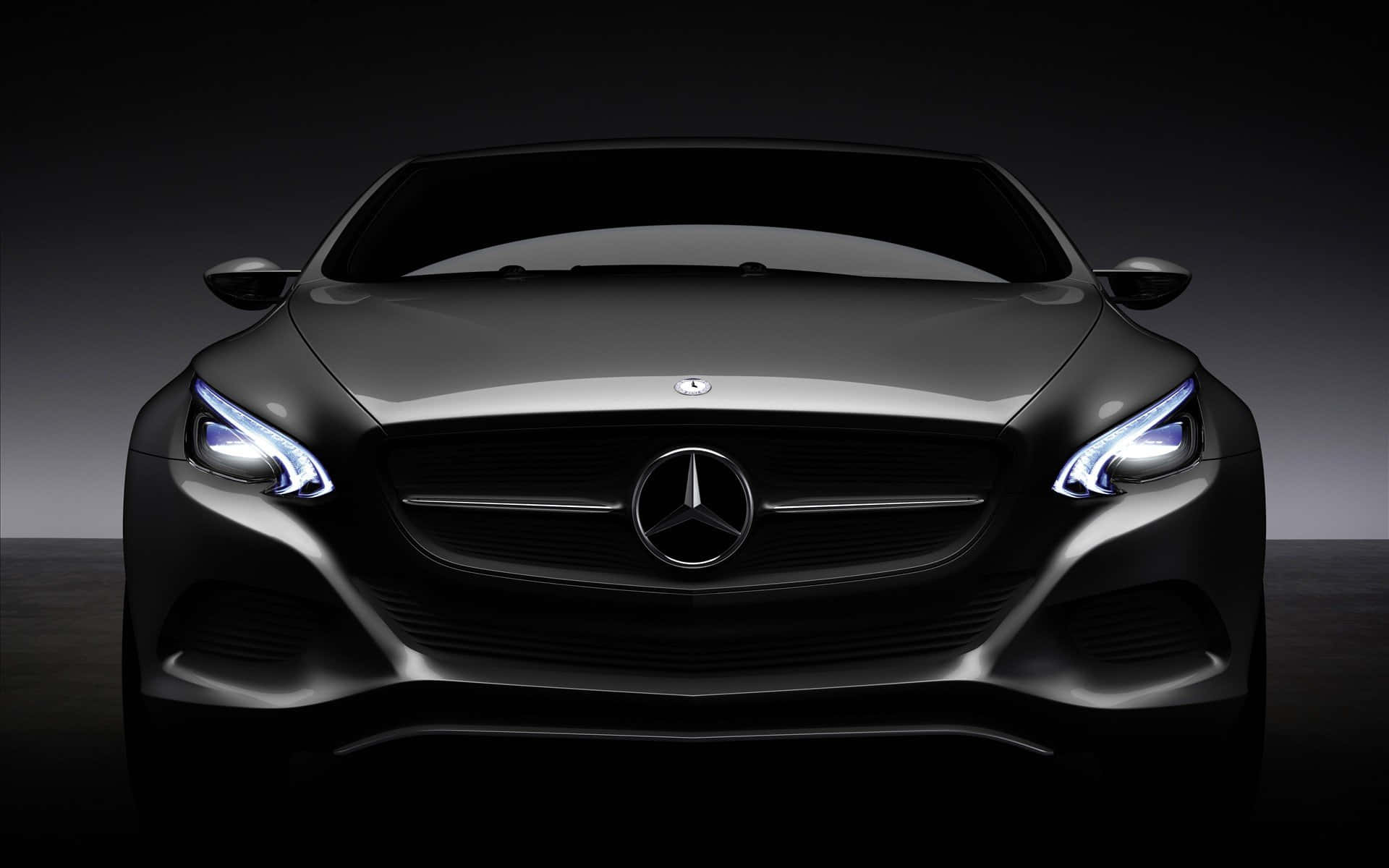 Mercedes 桌布 壁紙 — 一輛時尚的黑色賓士汽車在黑暗的攝影棚背景下散發出銳利的車頭燈光芒。