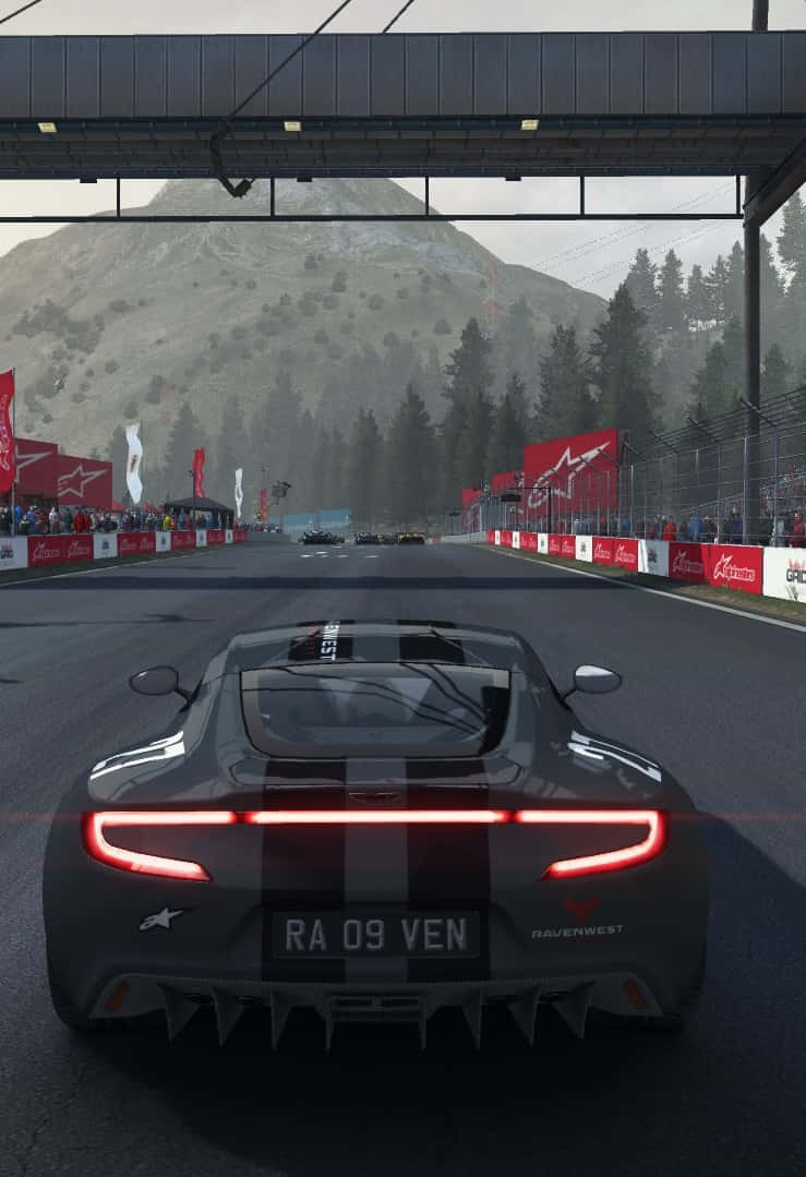 iPhone X Grid Autosport 桌布 壁紙 — 一輛時尚的黑色賽車，帶有發光的紅色尾燈，在擠滿觀眾和品牌障礙物的山間賽道上飛馳。
