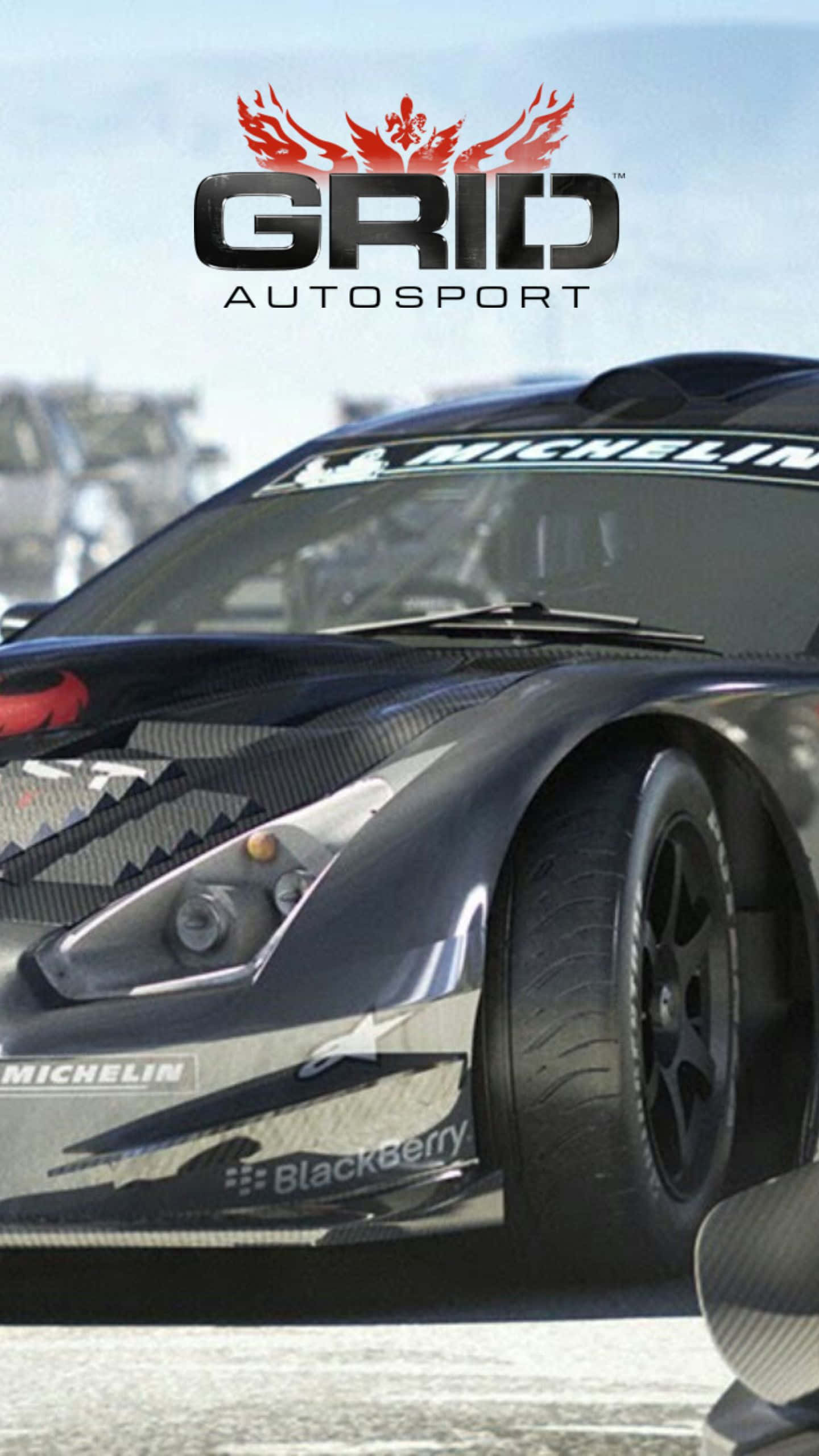 Android Grid Autosport 桌布 壁紙 — 一輛時尚的黑色賽車，帶有碳纖維細節和米其林品牌，在明亮的日光下主導賽道。