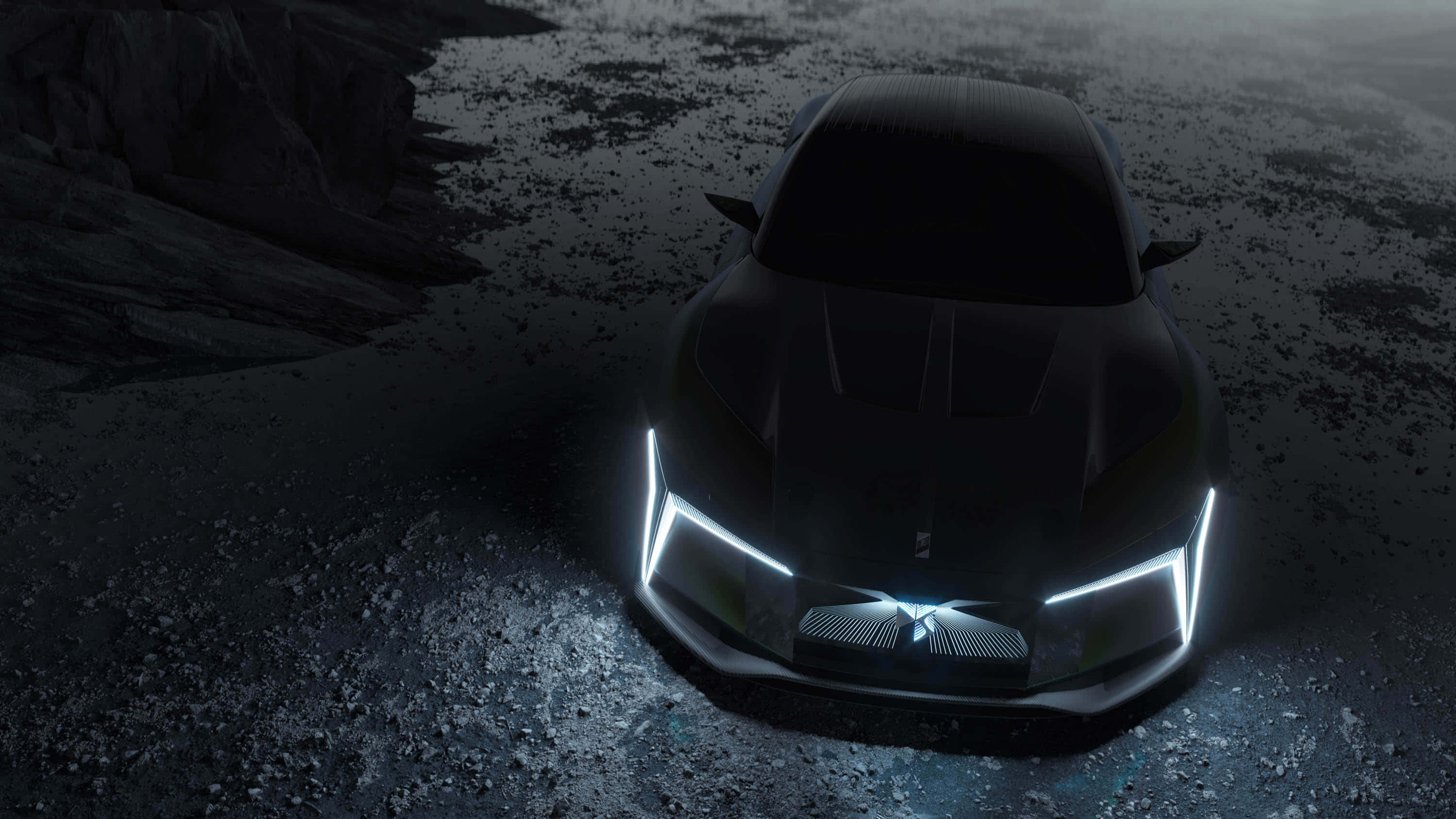 Ds Automobiles 桌布 壁紙 — 一輛時尚的黑色跑車，帶有發光的白色車頭燈，停放在黑暗天空下的岩石地形上。