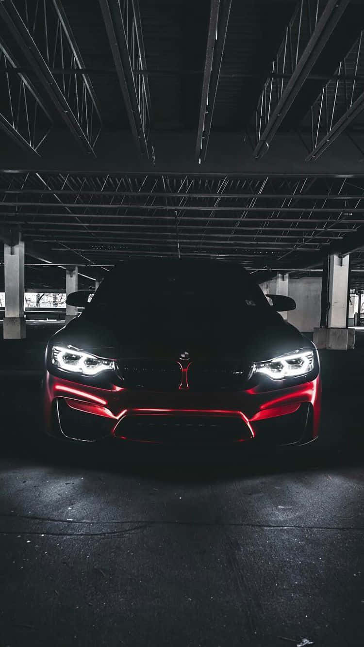 BMW 動圖 桌布 壁紙 — 一輛時尚的黑色跑車，帶有發光的紅色飾邊和明亮的車頭燈，主宰著昏暗的地下停車場。