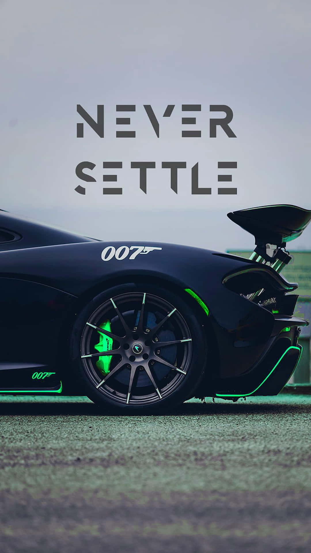  壁紙 — 一輛時尚的黑色跑車，帶有綠色裝飾和「007」品牌標誌，停泊在陰天下的賽道上，上方有「NEVER SETTLE」文字。
