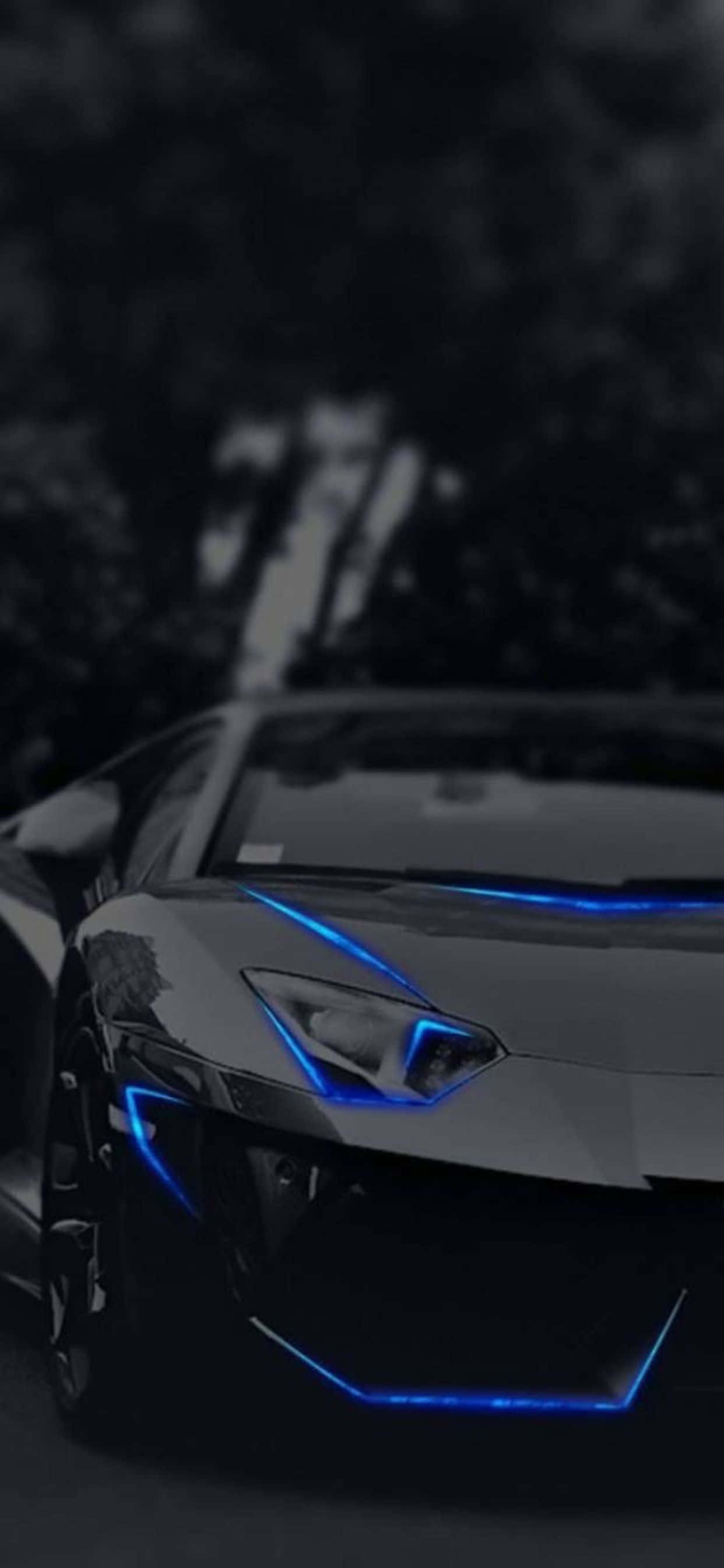 Lamborghini Phone 桌布 壁紙 — 一輛時尚的黑色跑車，帶有藍色底盤燈，夜晚停在黑暗的森林中。