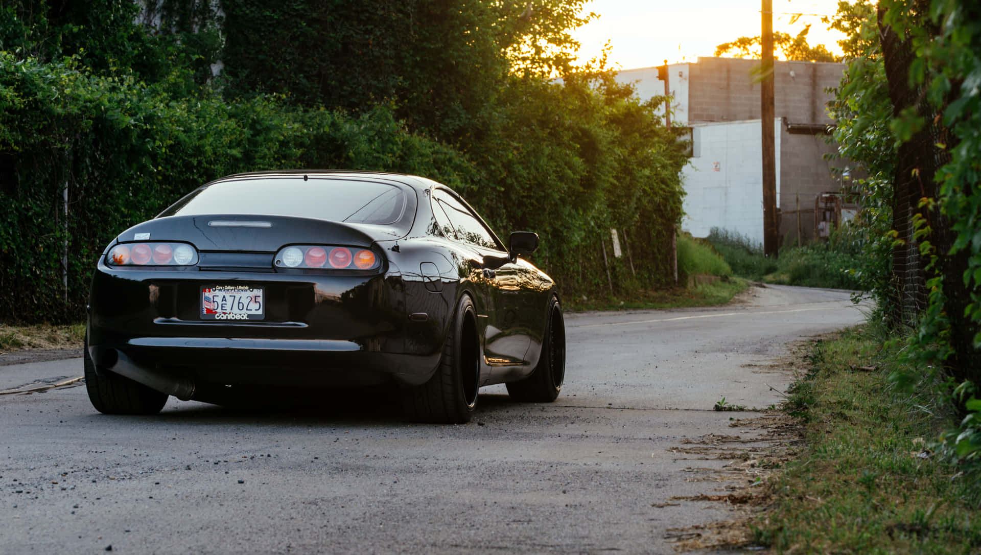 日落時分，黑色跑車停在綠樹成蔭的道路上。 — Toyota Supra Mk4 壁紙