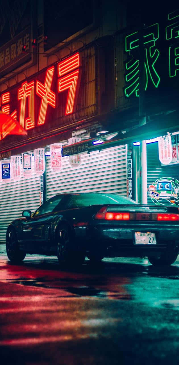 JDM 桌布 壁紙 — 一輛時尚的黑色跑車停在潮濕的霓虹燈街道上，夜晚反射出鮮豔的紅色和綠色招牌。