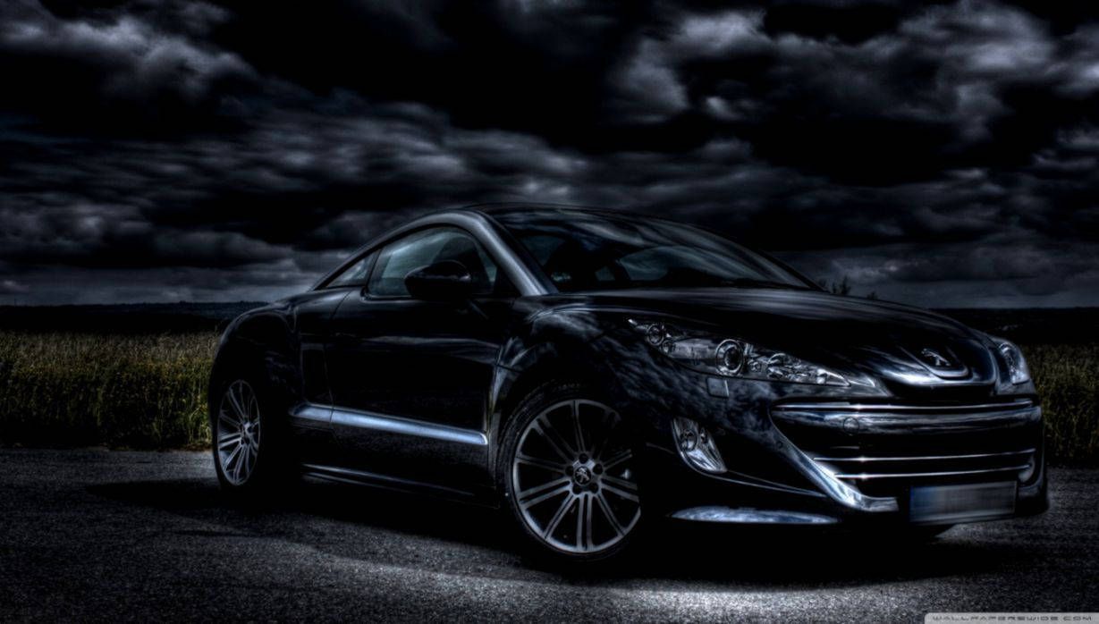 Peugeot 桌布 壁紙 — 一輛時尚的黑色跑車在夜間荒涼的田野中，在戲劇性的暴風雲下閃閃發光。