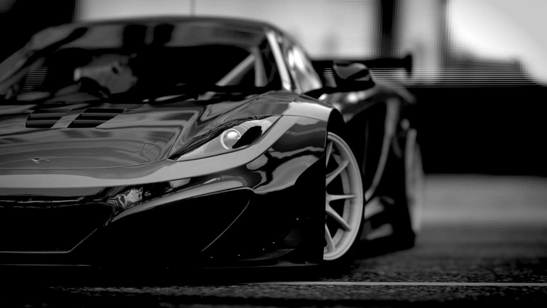 1920 X 1080 Car 桌布 壁紙 — 一輛時尚的黑色跑車在戲劇性燈光下閃耀，淺景深凸顯其空氣動力學曲線和銳利線條。