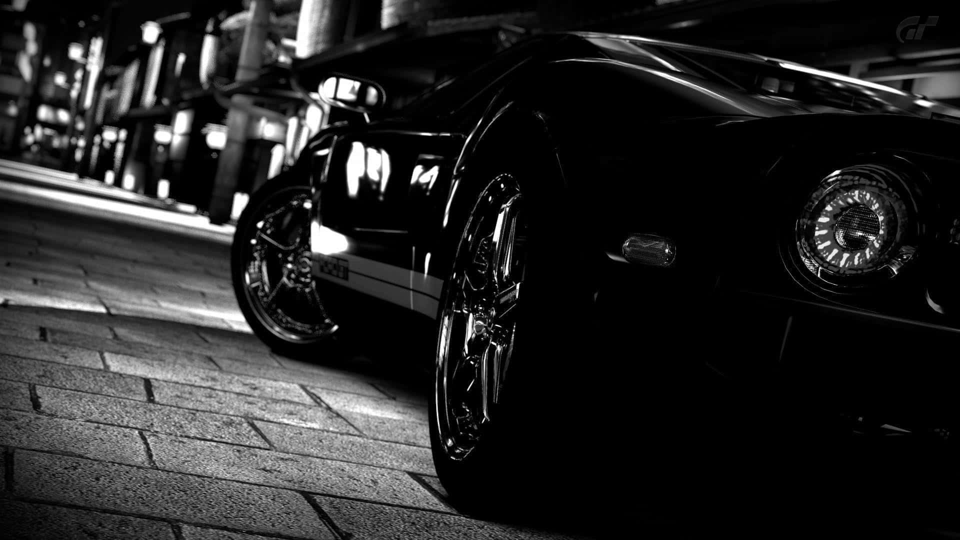 Black And White Car 桌布 壁紙 — 一輛時尚的黑色跑車在戲劇性的夜間燈光下，在濕漉漉的鵝卵石街道上閃閃發光。