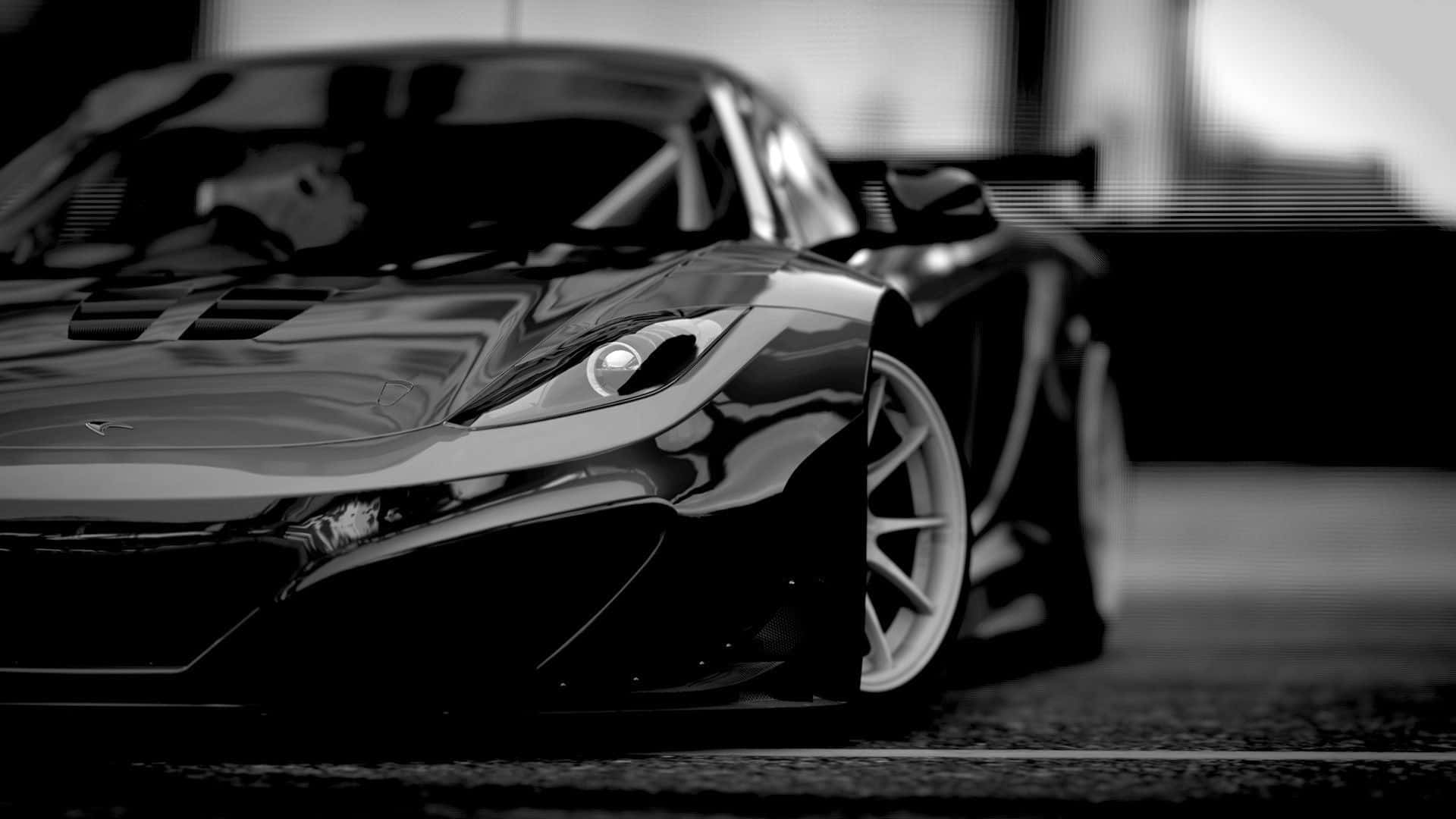Black And White Car 桌布 壁紙 — 一輛時尚的黑色跑車在戲劇性的燈光下閃耀，淺景深突出了其空氣動力學曲線和銳利線條。