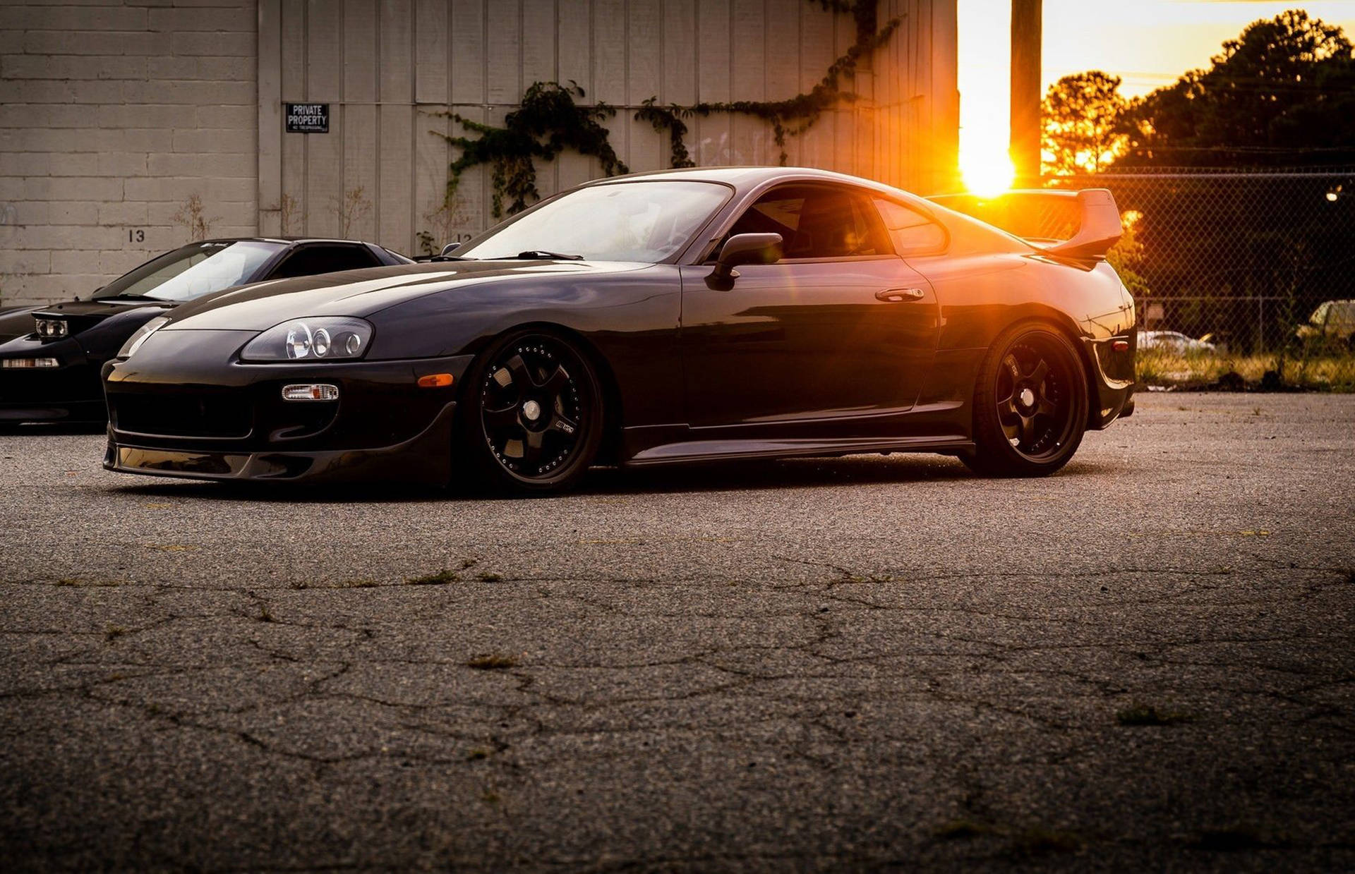 黑色跑車停在裂縫瀝青上，夕陽下，靠近圍欄 — Toyota Supra Mk4 壁紙