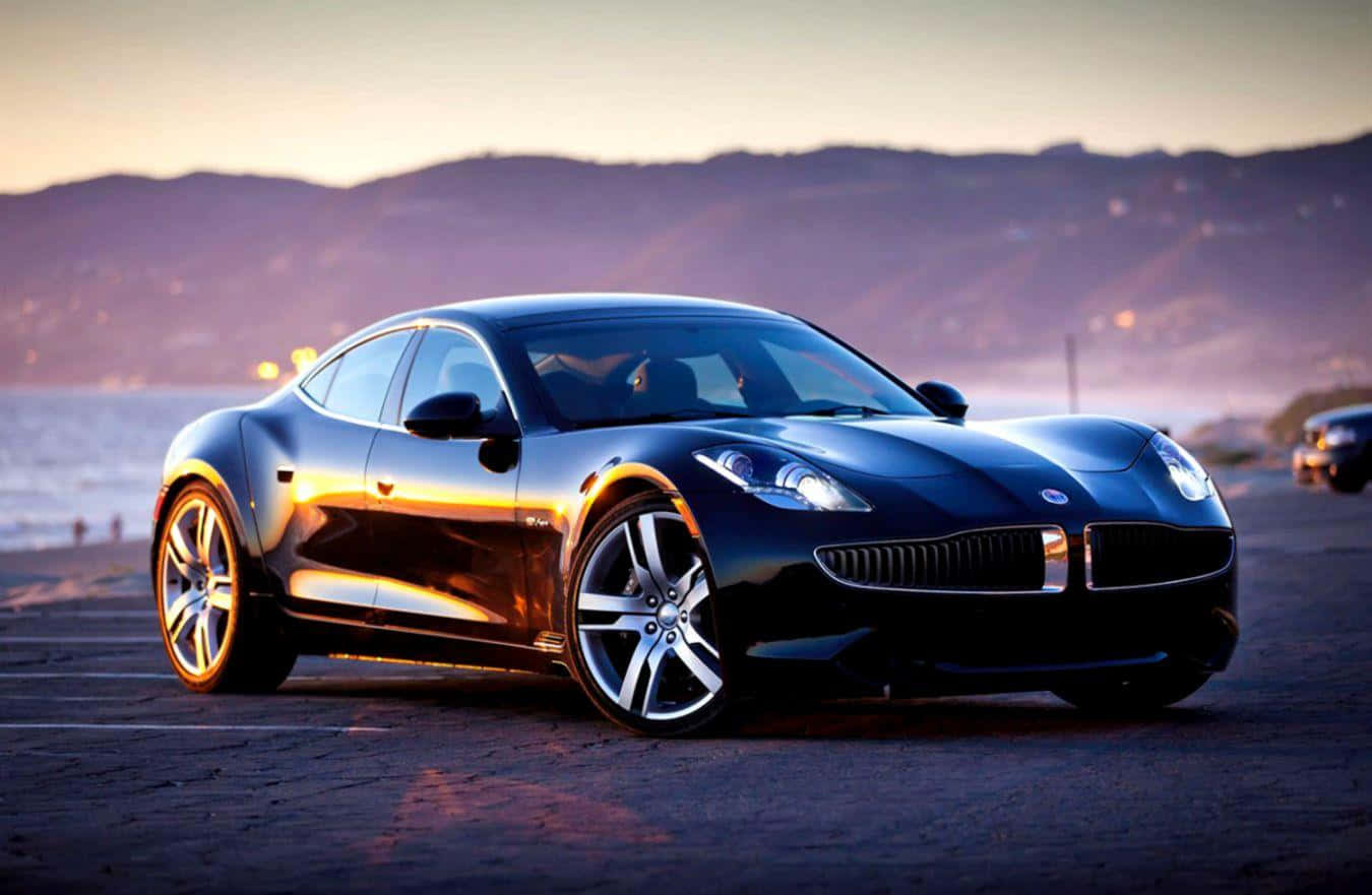 Fisker 桌布 壁紙 — 一輛時尚的黑色跑車在金色夕陽下閃閃發光，停泊在沿海公路上，背景是山丘。